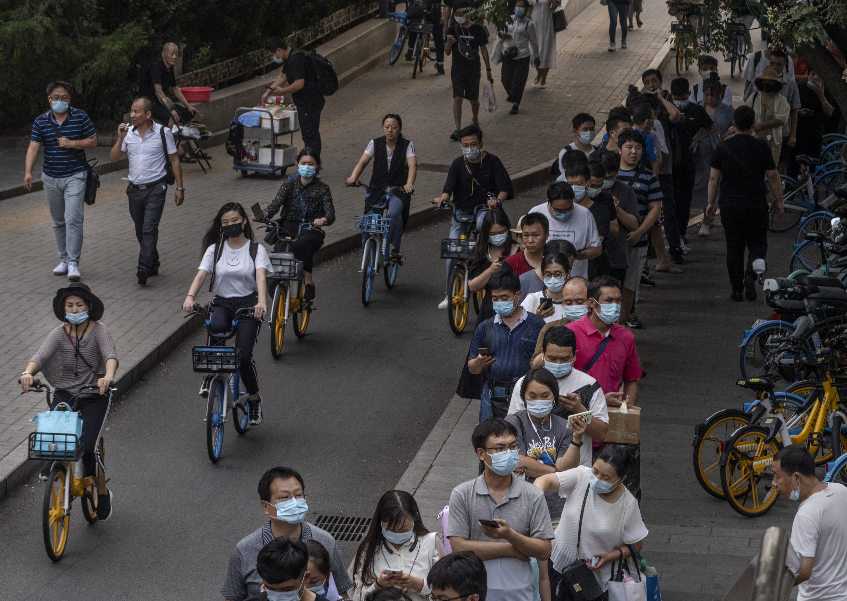 Commuters, many wearing masks to protect against COVID-19, wait to board a public bus during the evening rush hour on Aug. 4, 2021 in Beijing.