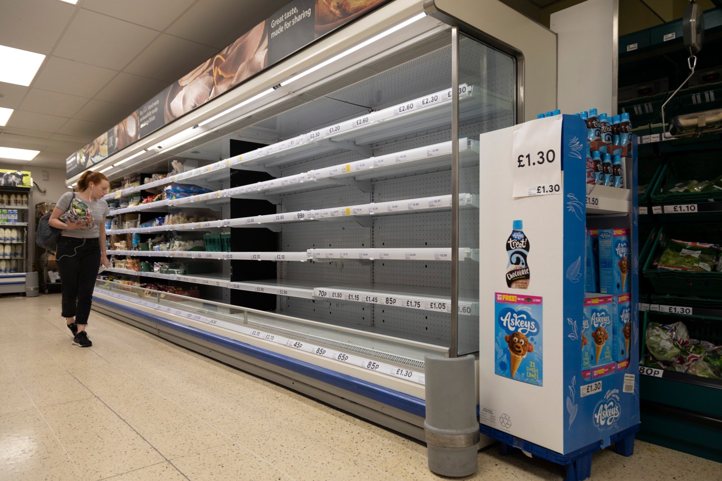 A shopper stands by empty shelves with no stock on them in a Tesco on 22nd July, 2021 in Leeds, United Kingdom.