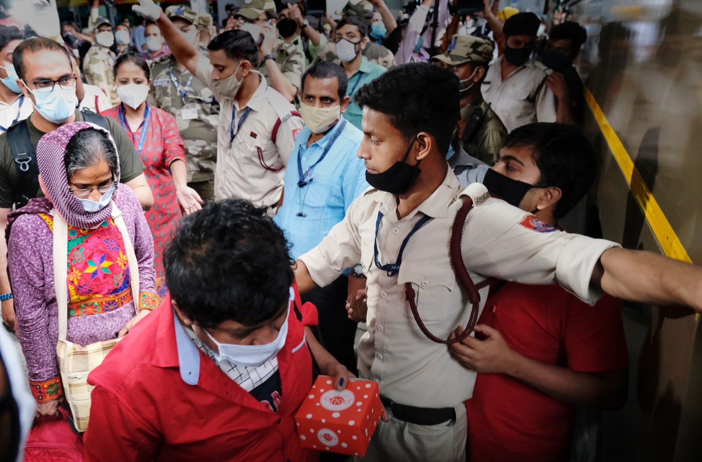 Indian and Afghan evacuees from Kabul are escorted by members of the Indo-Tibetan Border Police to a bus bound for a quarantine center upon arrival at Indira Gandhi International Airport in New Delhi, India, on Tuesday, Aug. 24, 2021. Civilian evacuations at Kabul airport must now end within the next few days to allow enough time to get remaining U.S. and other troops out.
