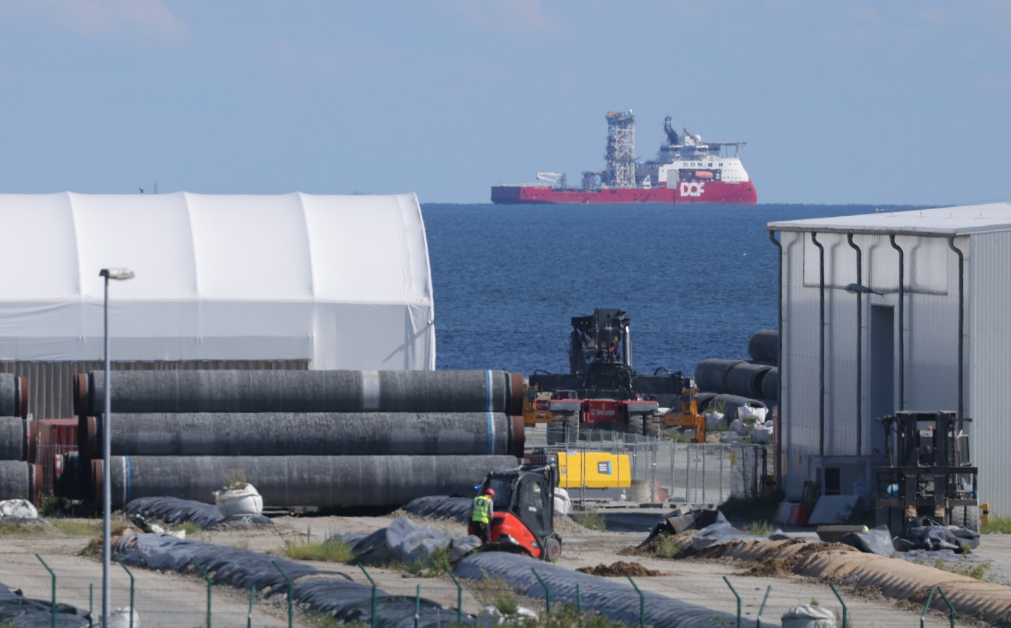 A ship of DOF Subsea, a Norwegian company that does subsea work for oil and gas companies, stands offshore next to pipe sections for the Nord Stream 2 pipeline stacked at Mukran Port on Rügen Island on August 04, 2021 in Sassnitz, Germany. Mukran Port is the main German operating base for supplying pipe sections to the Nord Stream 2 gas pipeline, a dual line pipeline that runs along the Baltic Sea floor and will transport natural gas from Russia to Germany.