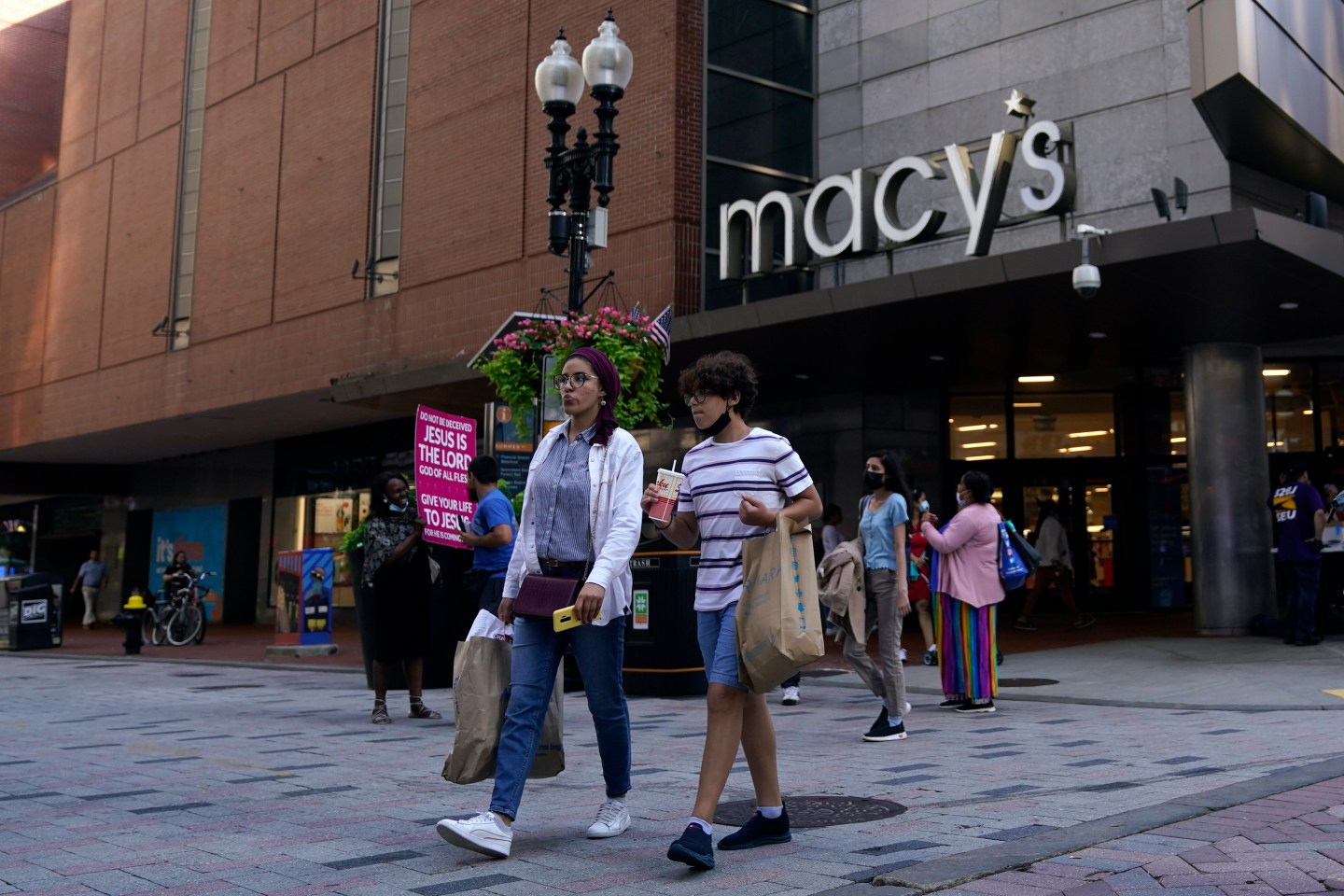 FILE &#8211; In this July 14, 2021 file photo, pedestrians pass the Macy&#8217;s store in the Downtown Crossing shopping area, in Boston.   Americans cut back on their spending last month as a surge in COVID-19 cases kept people away from stores. Retail sales fell a seasonal adjusted 1.1% in July from the month before, the U.S. Commerce Department said Tuesday, Aug. 17.   (AP Photo/Charles Krupa, File)
