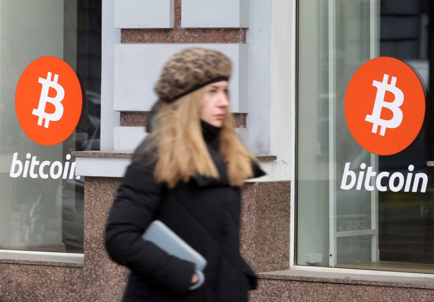 A woman walks past an office of Bitcoin (BTC) cryptocurrency