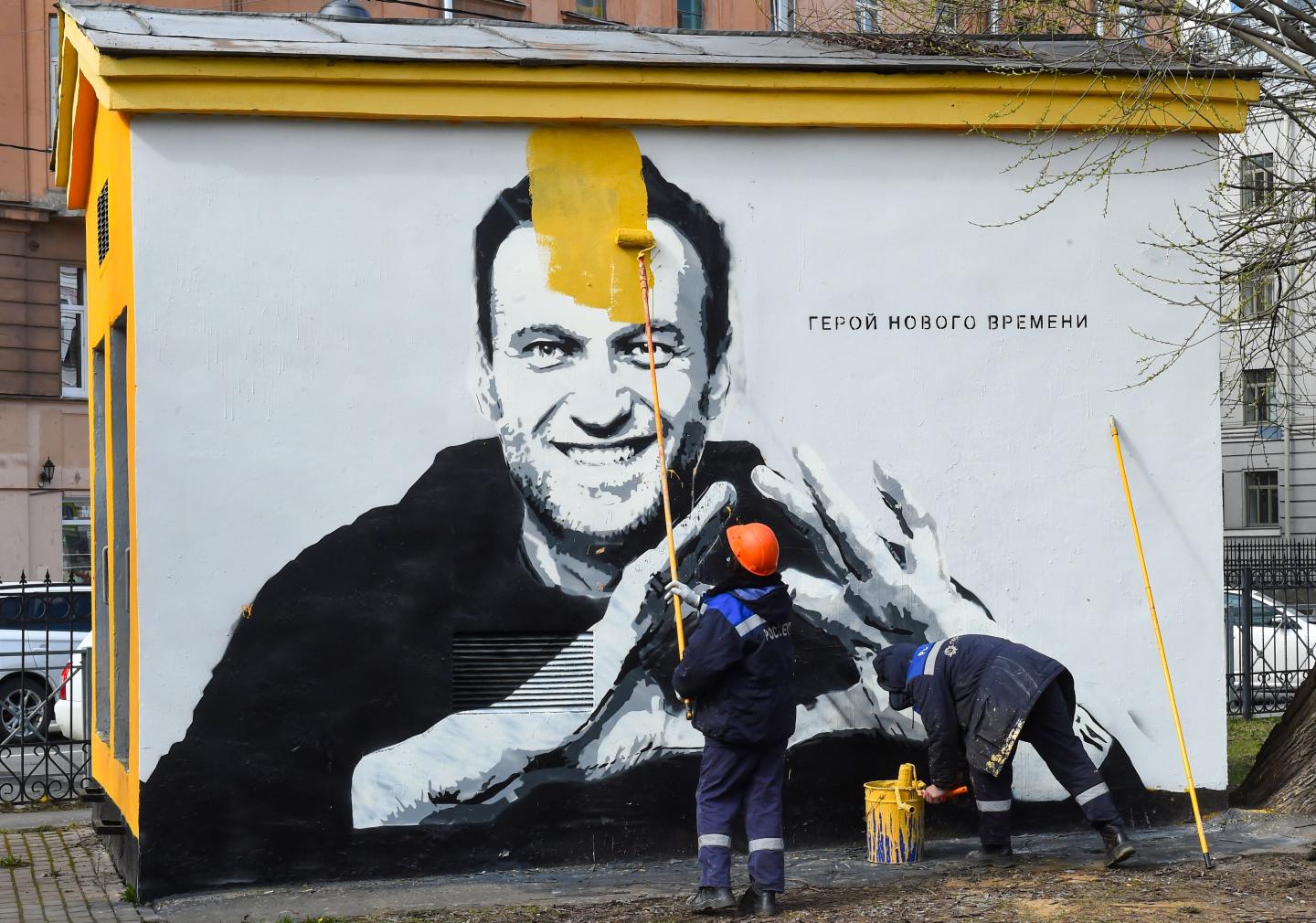 A worker paints over graffiti of jailed Kremlin critic Alexei Navalny in Saint Petersburg on April 28, 2021. The inscription reads: "The hero of the new times".