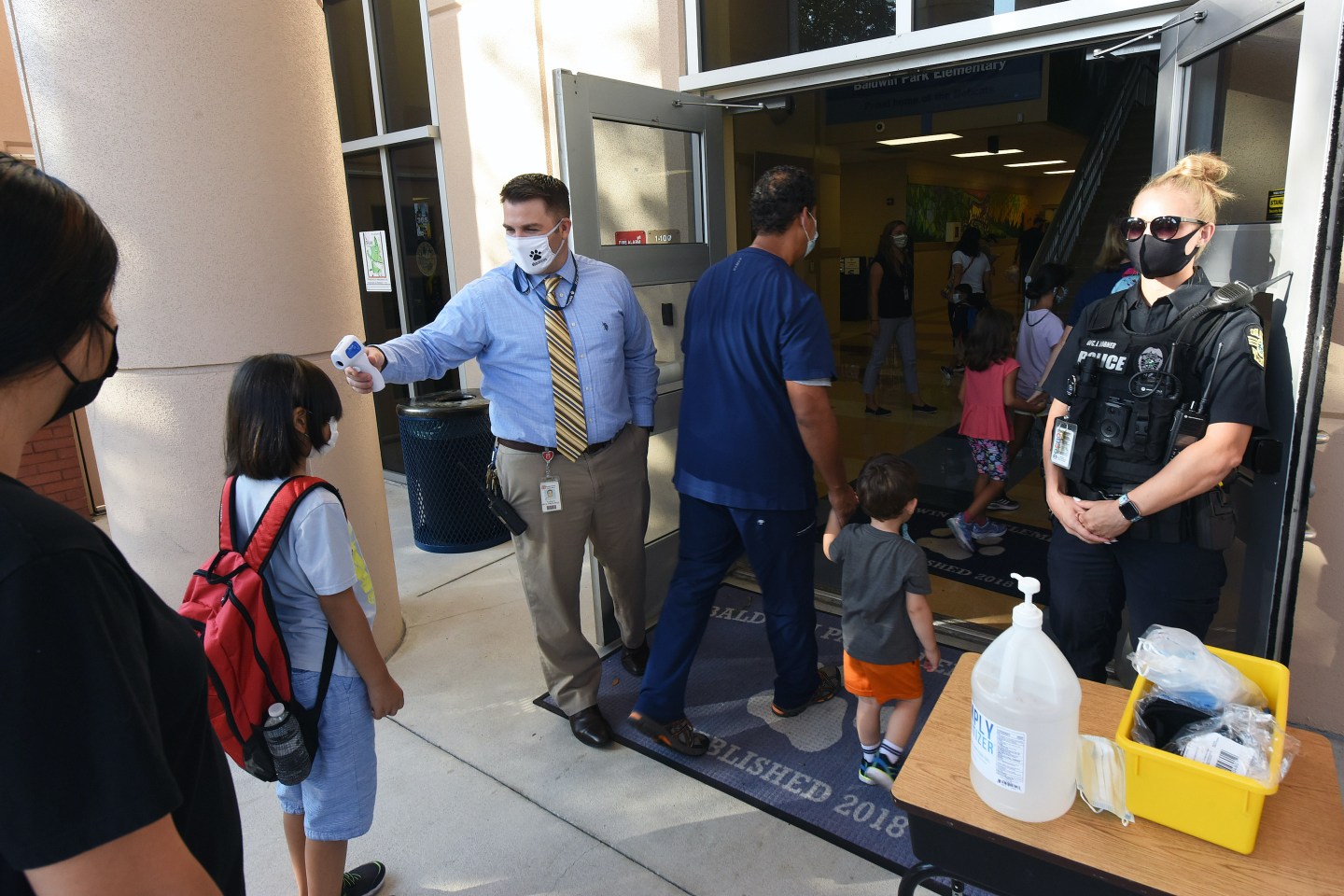 A principal in Orlando performs temperature checks on students arriving at school.