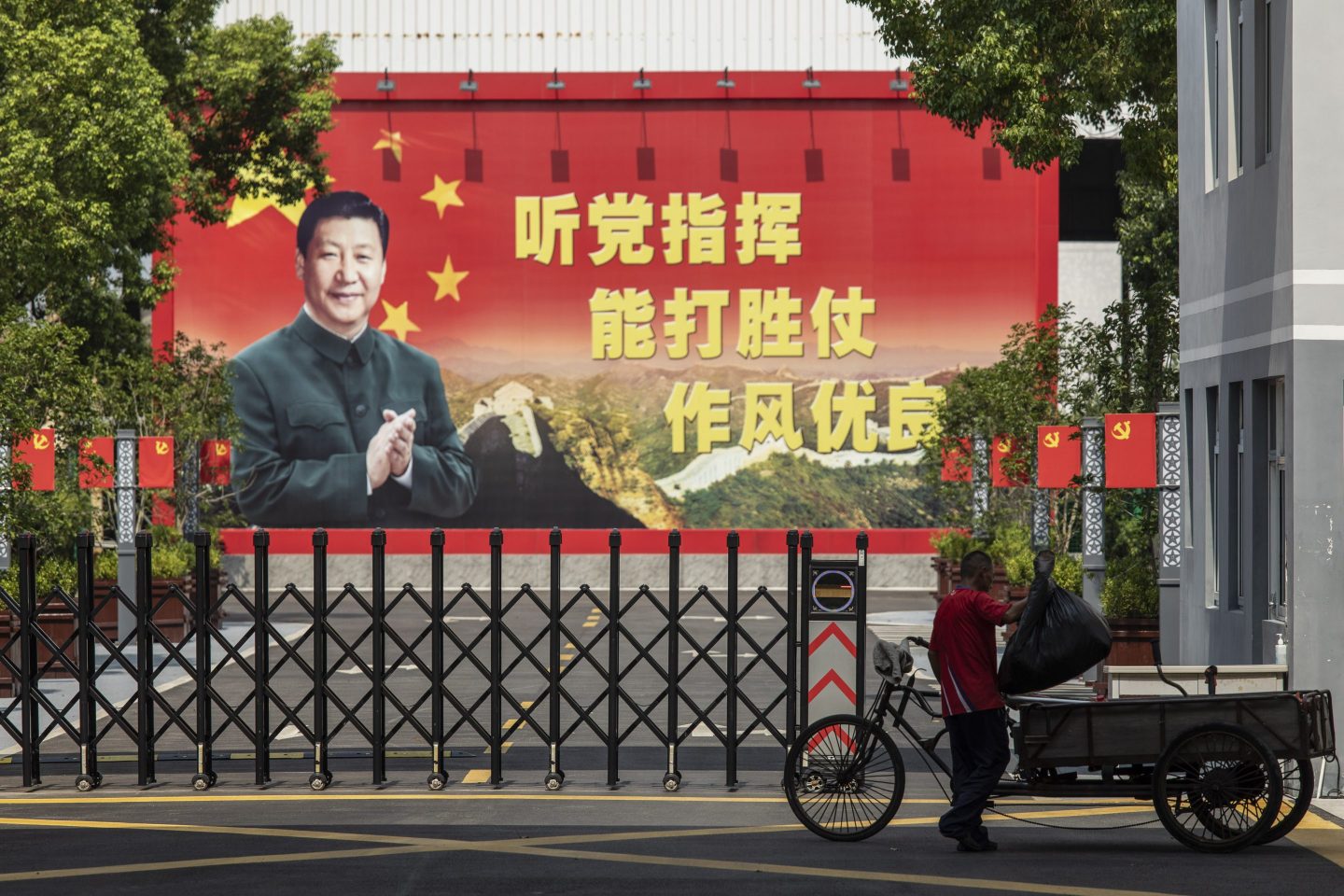 A man places a bag of trash into his rickshaw in front of a compound displaying a billboard featuring China&#8217;s President Xi Jinping in Shanghai, China, on Monday, Aug. 30, 2021. Chinese President Xi Jinping chaired a high-level meeting that reviewed and approved measures to fight monopolies, battle pollution and shore up strategic reserves, all areas that are crucial to his governments push to improve the quality of life for the nations 1.4 billion people. Photographer: Qilai Shen/Bloomberg via Getty Images