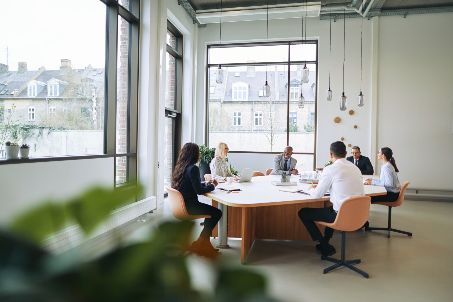 Smiling group of diverse businesspeople sitting around a boardroom table in an office during a meeting