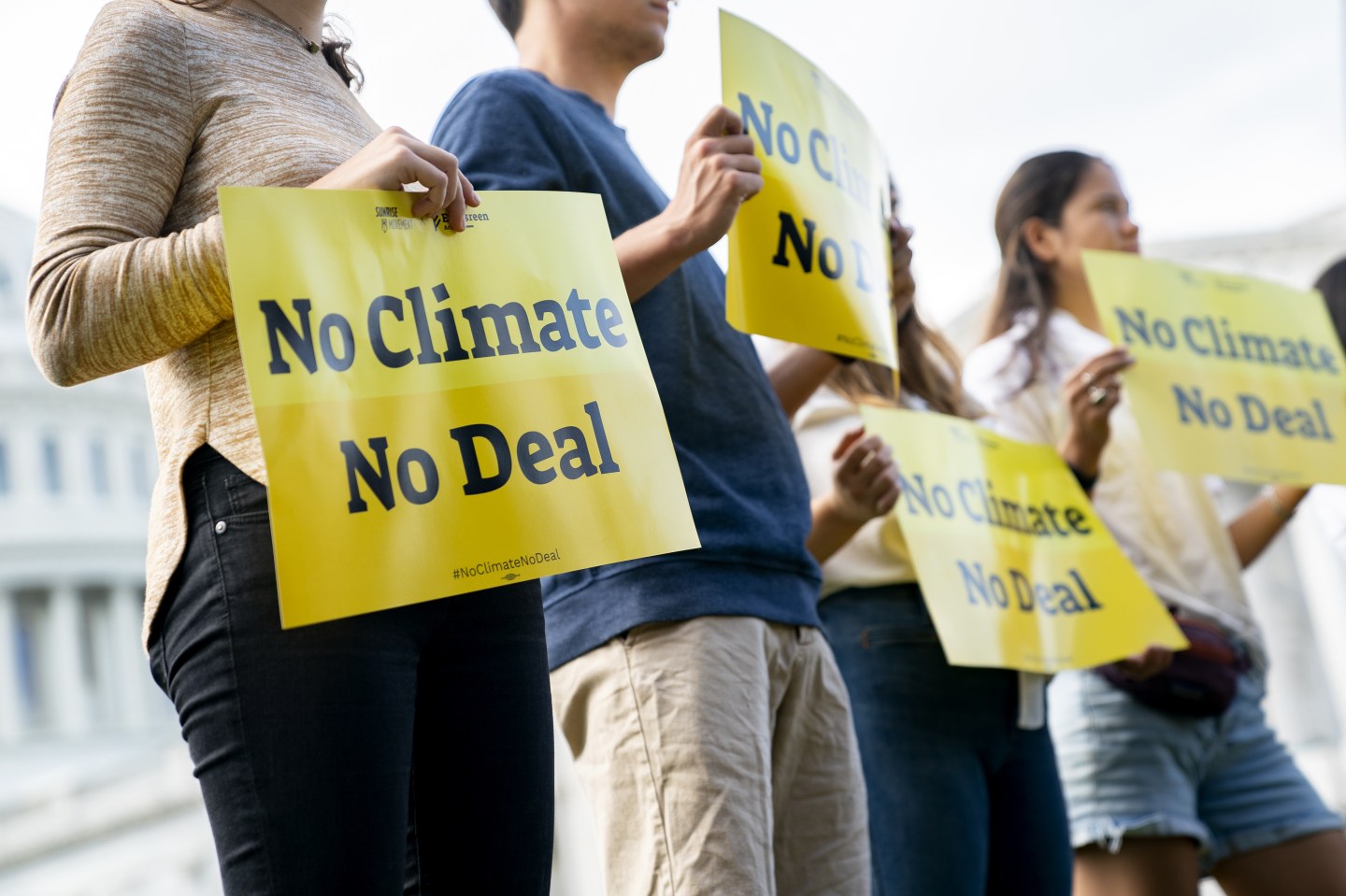 Climate activists hold signs outside the U.S. Capitol on Oct. 7. “The toll of climate change will only worsen if Congress fails to make commonsense climate investments now,” writes Liz O’Neill.
