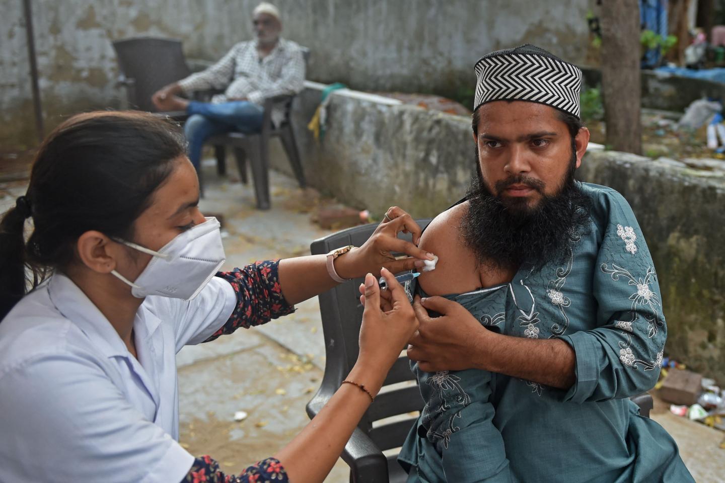A health worker inoculates a man with a dose of the Covishield vaccine against the Covid-19 coronavirus at a vaccination centre organised by the city police and municipal corporation during a drive to provide free one litre of cooking oil to beneficiaries getting vaccinated in Ahmedabad on October 10, 2021.