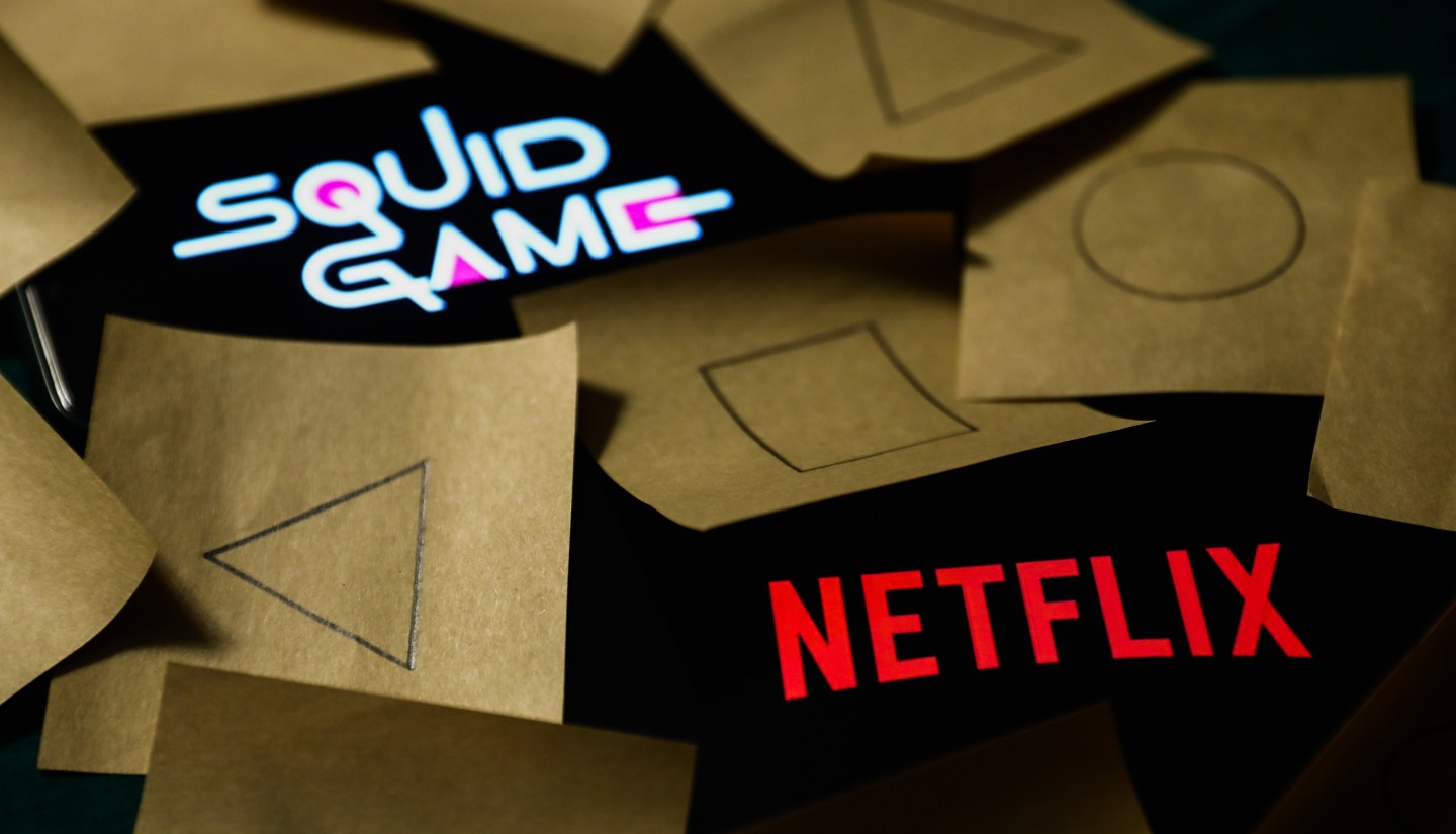 Netflix and Squid Game series logos displayed on a phone screens are seen with symbols known from the series, drawn on pieces of paper, in this illustration photo taken in Krakow, Poland on October 18, 2021.