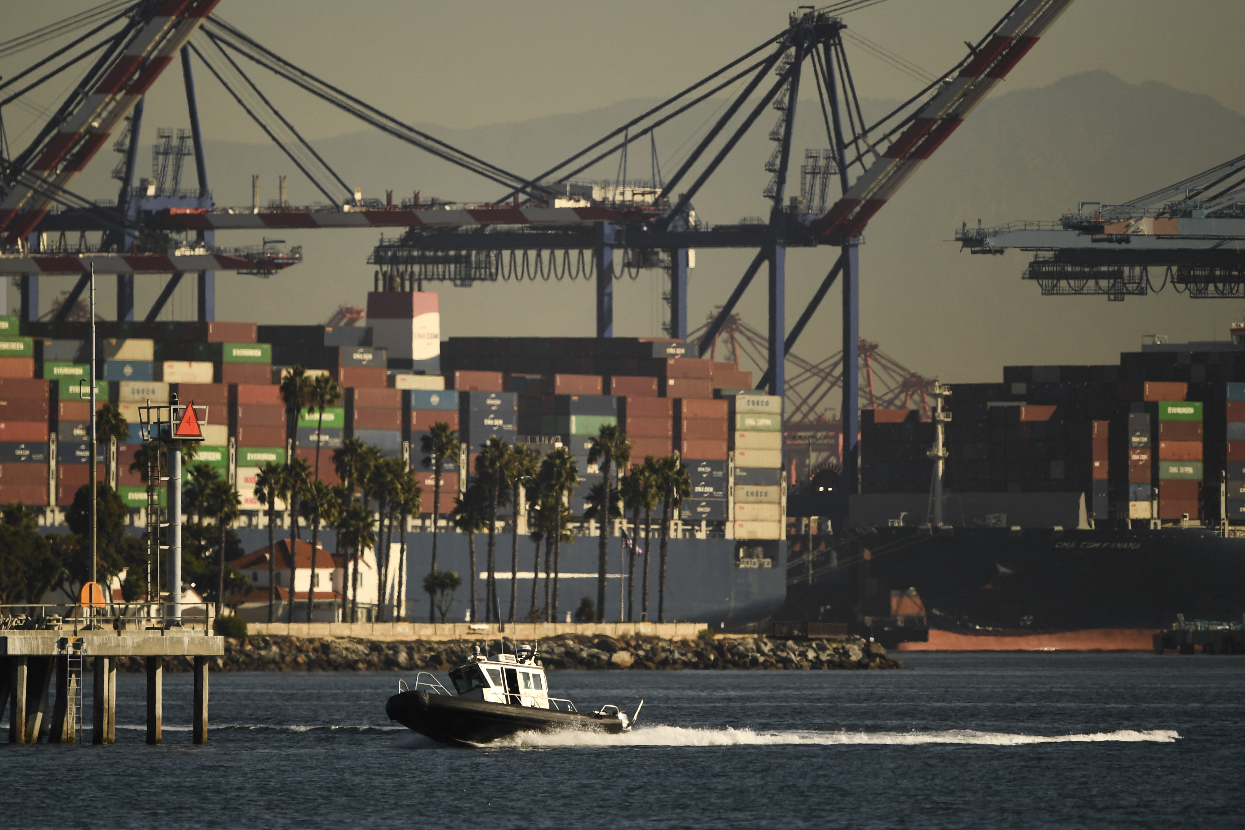 Cranes and stacks of cargo shipping containers stand at the Port of Los Angeles. The Biden Administration's plan to keep the port open 24/7 is not easing the flow of goods so far, a shipping CEO says.