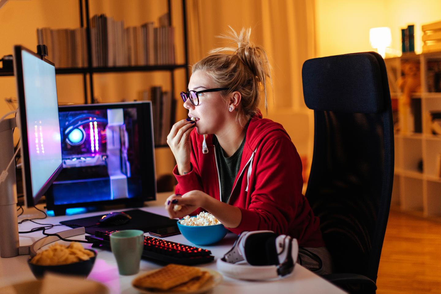 woman looking at a computer eating snacks