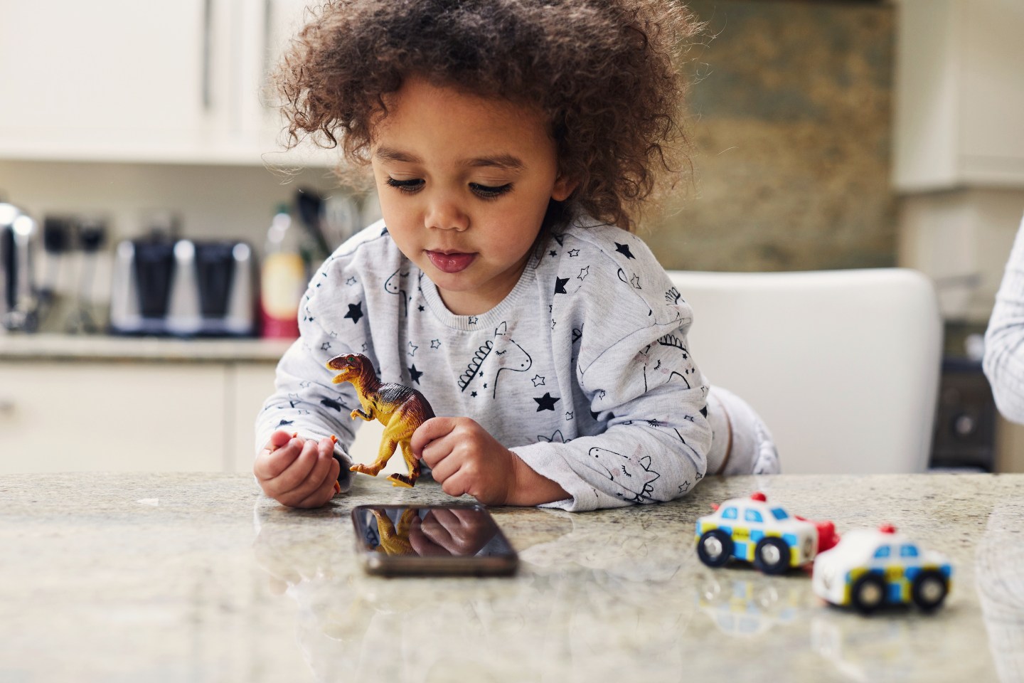 Photo of girl playing with toy dinosaurs and cars