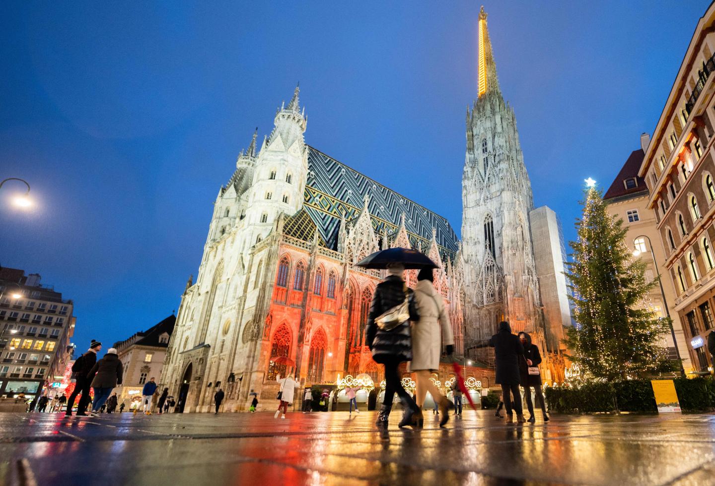 People walk past the closed "Christkindlmarkt" Vienna's Christmas Market, and St Stephen's Cathedral in Vienna, Austria, on November 22, 2021, during the ongoing coronavirus (Covid-19) pandemic.