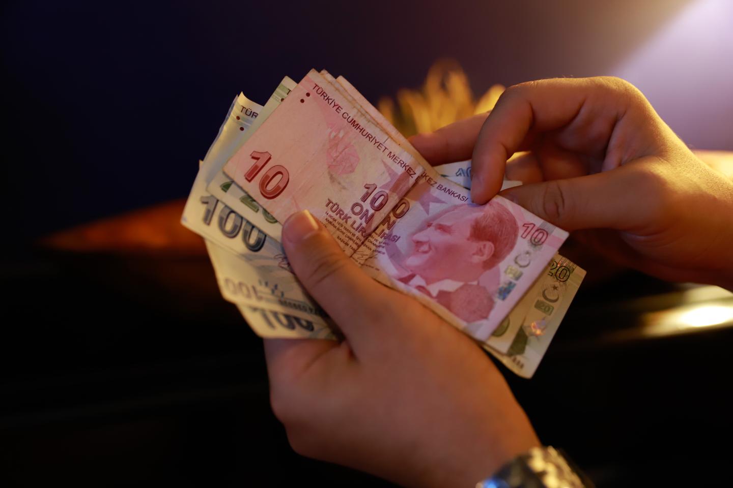 A man holds banknotes of the Turkish lira at a cafe in Izmir, Turkey, on Monday, October 11, 2021.