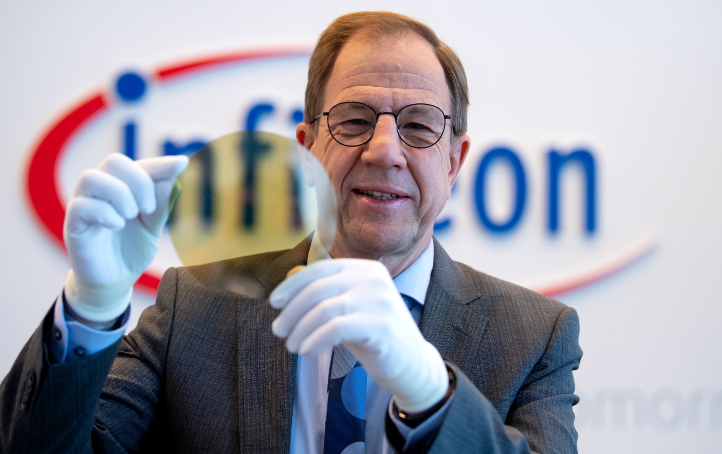 Reinhard Ploss, Infineon CEO, shows a wafer before the start of the annual press conference at the semiconductor manufacturer's headquarters.