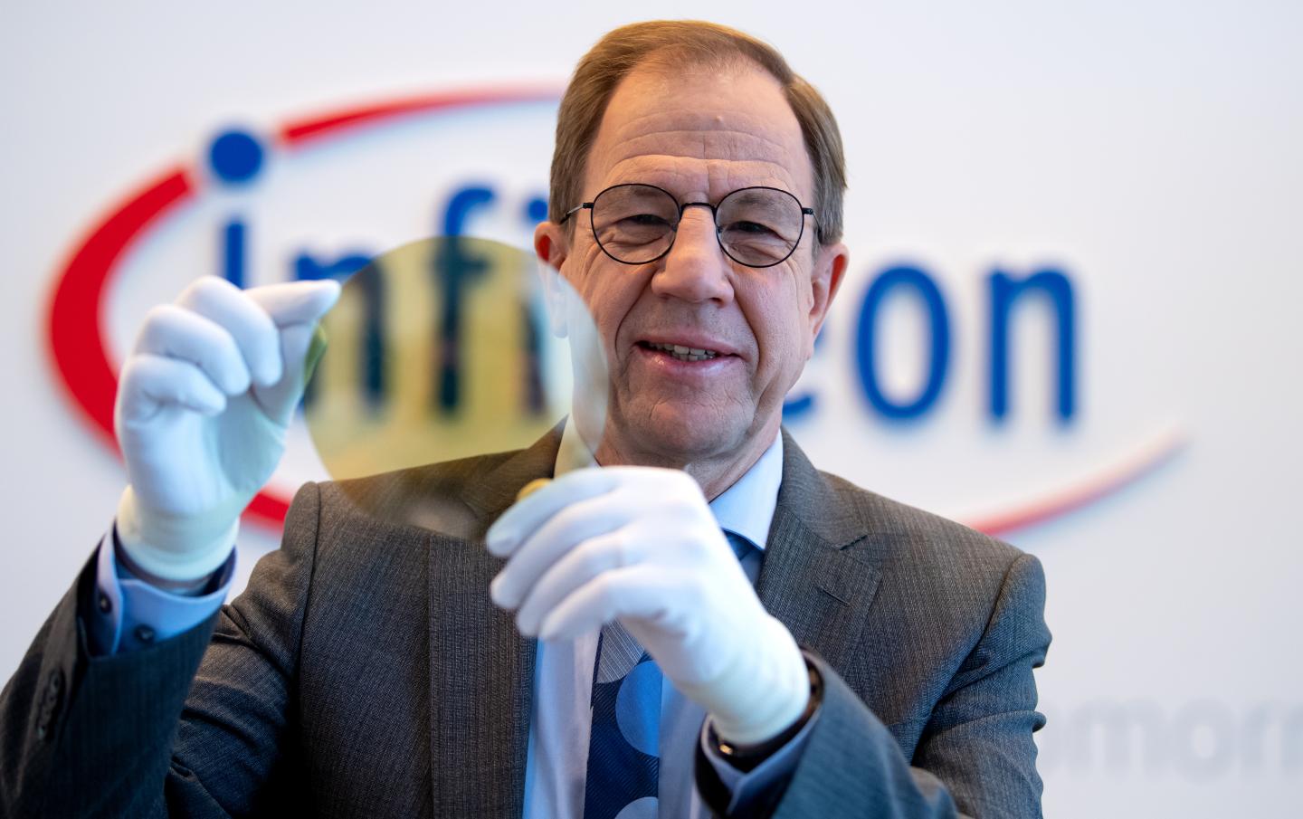 Reinhard Ploss, Infineon CEO, shows a wafer before the start of the annual press conference at the semiconductor manufacturer's headquarters.