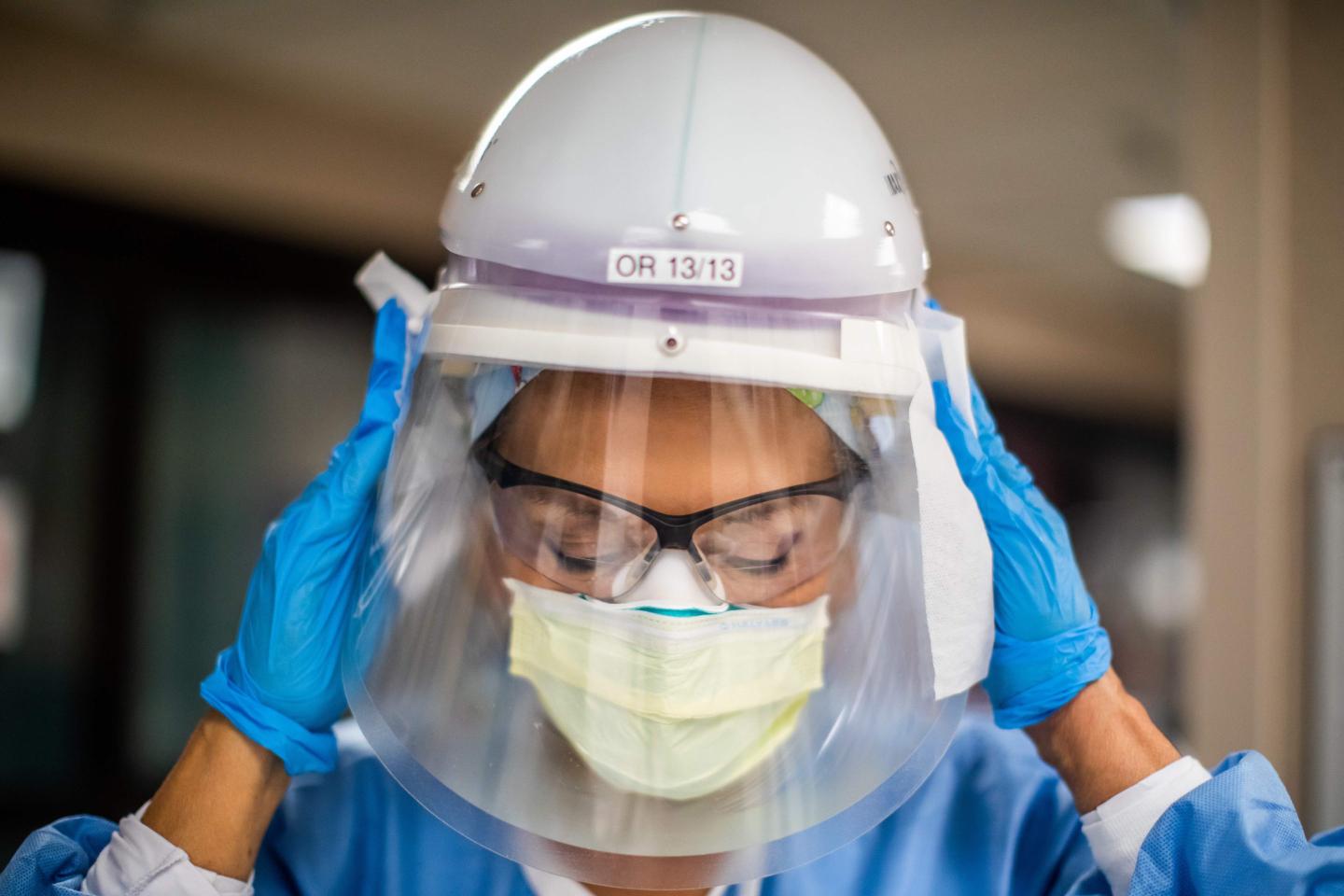 A nurse puts on her personal protective gear.