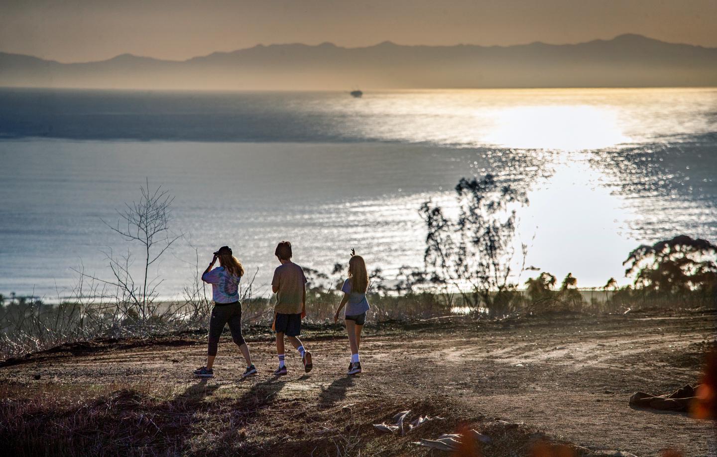 Three hikers enjoy an ocean view in California.