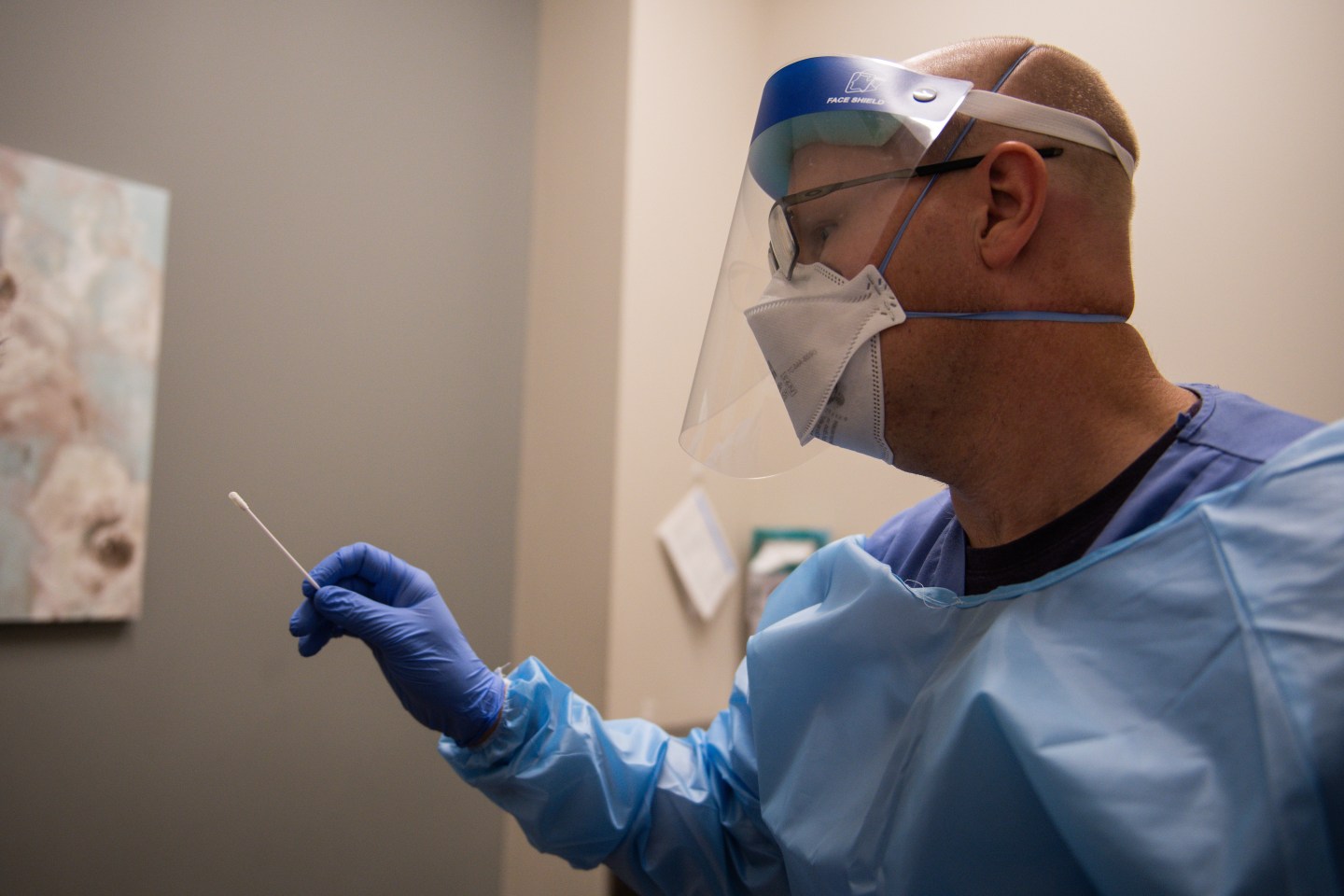 Photo of a health care worker holding a COVID test swab.