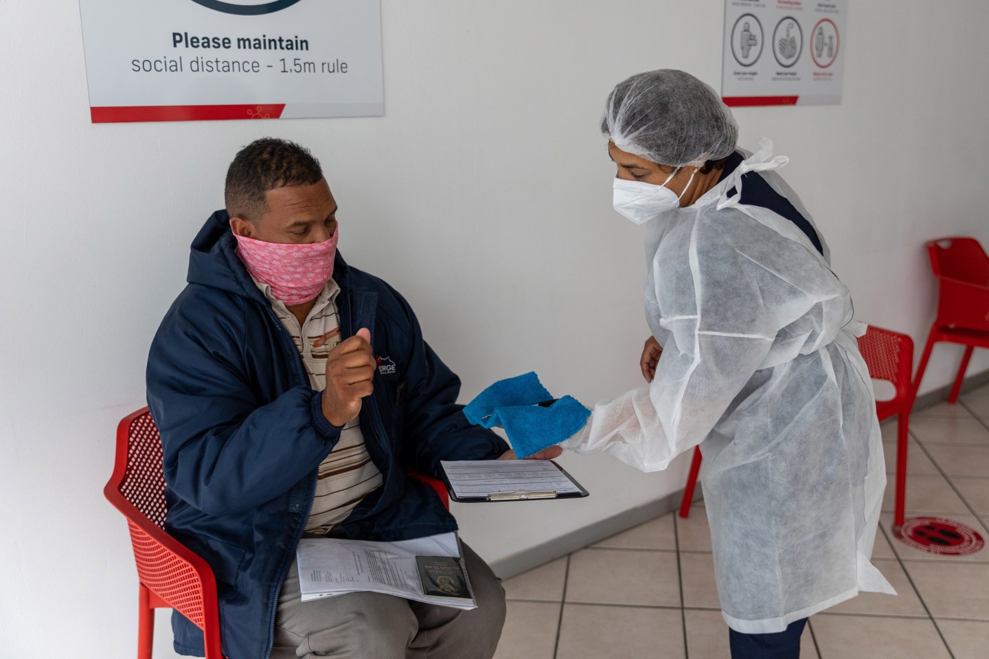 A health worker speaks with a patient in the reception area of a Testaro Covid-19 testing site in the Goodwood district of Cape Town, South Africa,