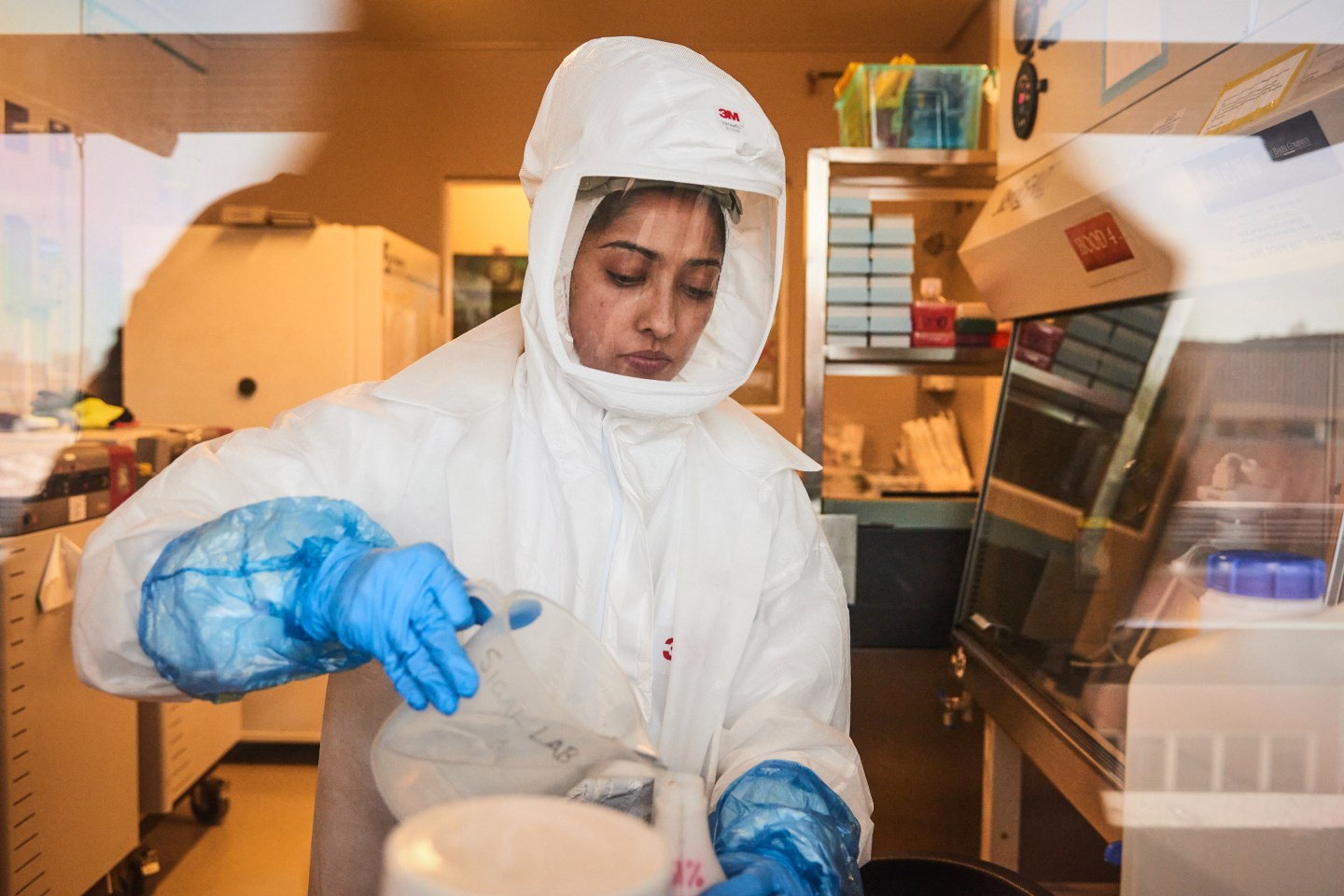 A technician wearing a full body protection suit pours material inside a biosafety level 3 Covid-19 research laboratory at the African Health Research Institute (AHRI) in Durban, South Africa, on Wednesday, Dec. 15, 2021. South Africas hospital admission rate as a percentage of new Covid-19 cases identified dropped sharply in the second week of the current infection wave driven by the omicron variant, compared with the same week of the third wave. Photographer: Waldo Swiegers/Bloomberg via Getty Images