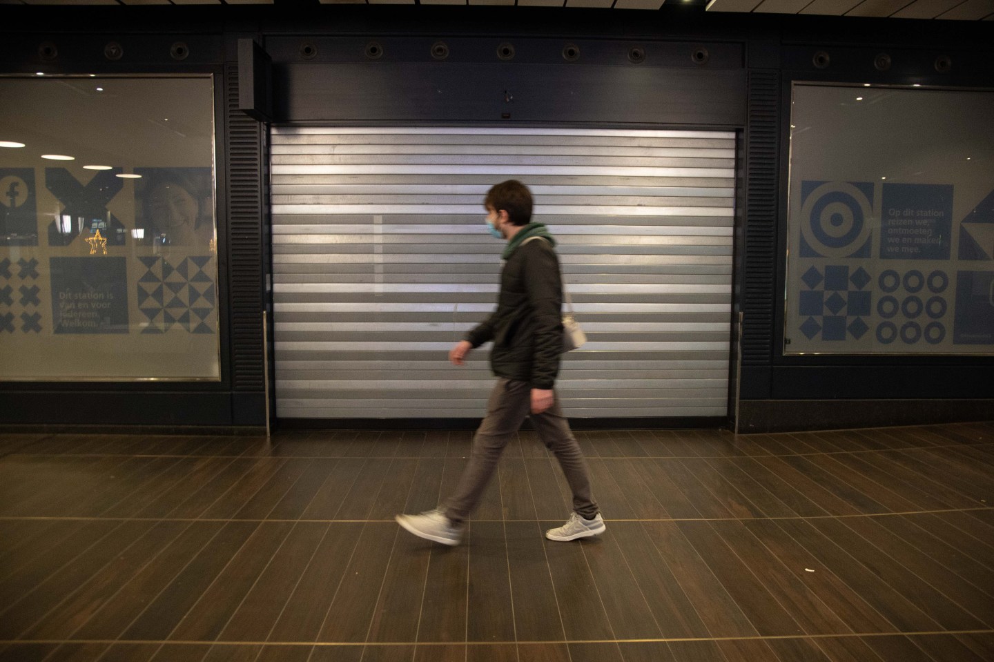 Person walking past a closed store in Amsterdam.