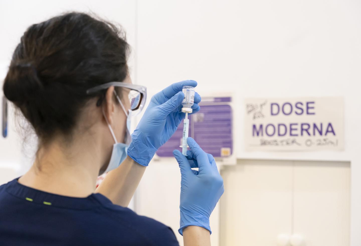 A health care worker prepares a Moderna booster vaccine dose.