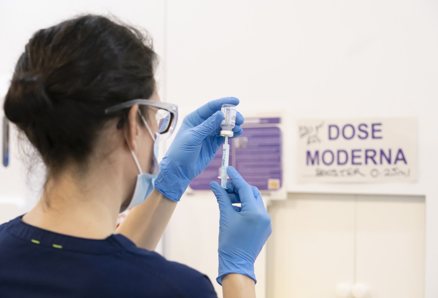 A health care worker prepares a Moderna booster vaccine dose.