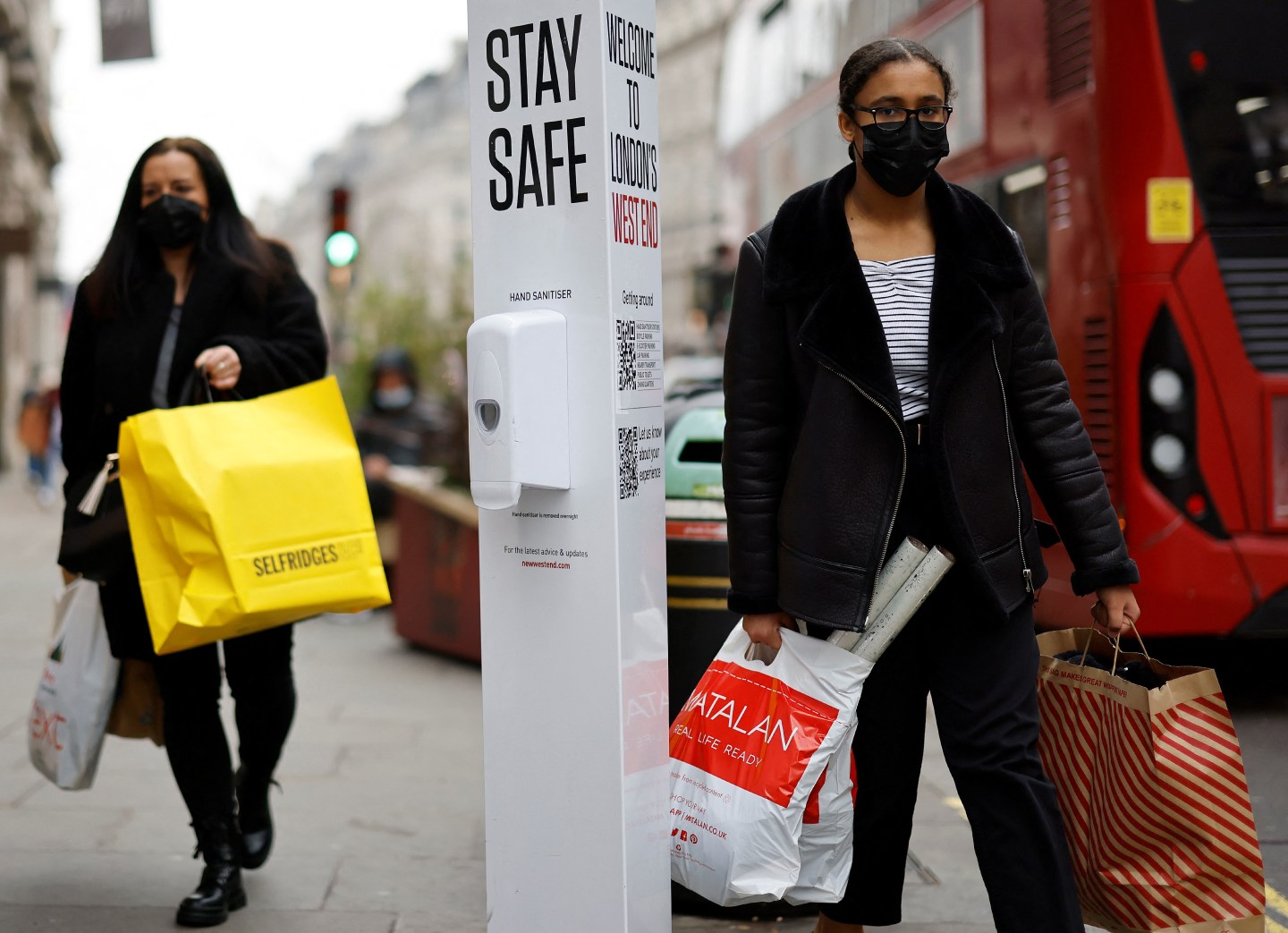 Members of the public, some wearing face coverings to help combat the spread of Covid-19, walk past a sign reading "Stay Safe" on Regent Street in London on December 21, 2021.