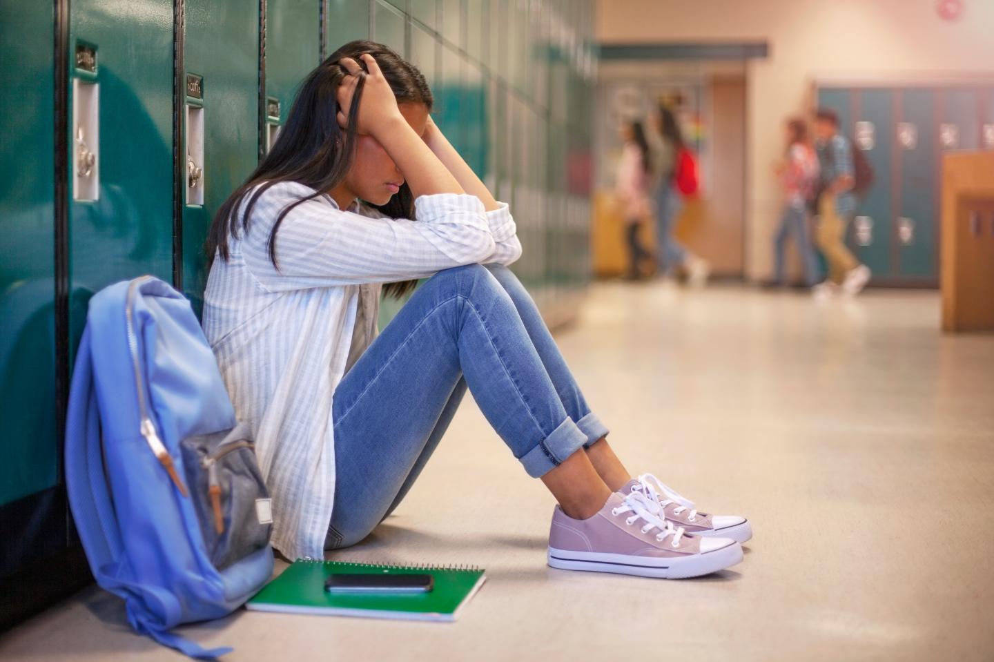 Female student sitting in a school hallway.