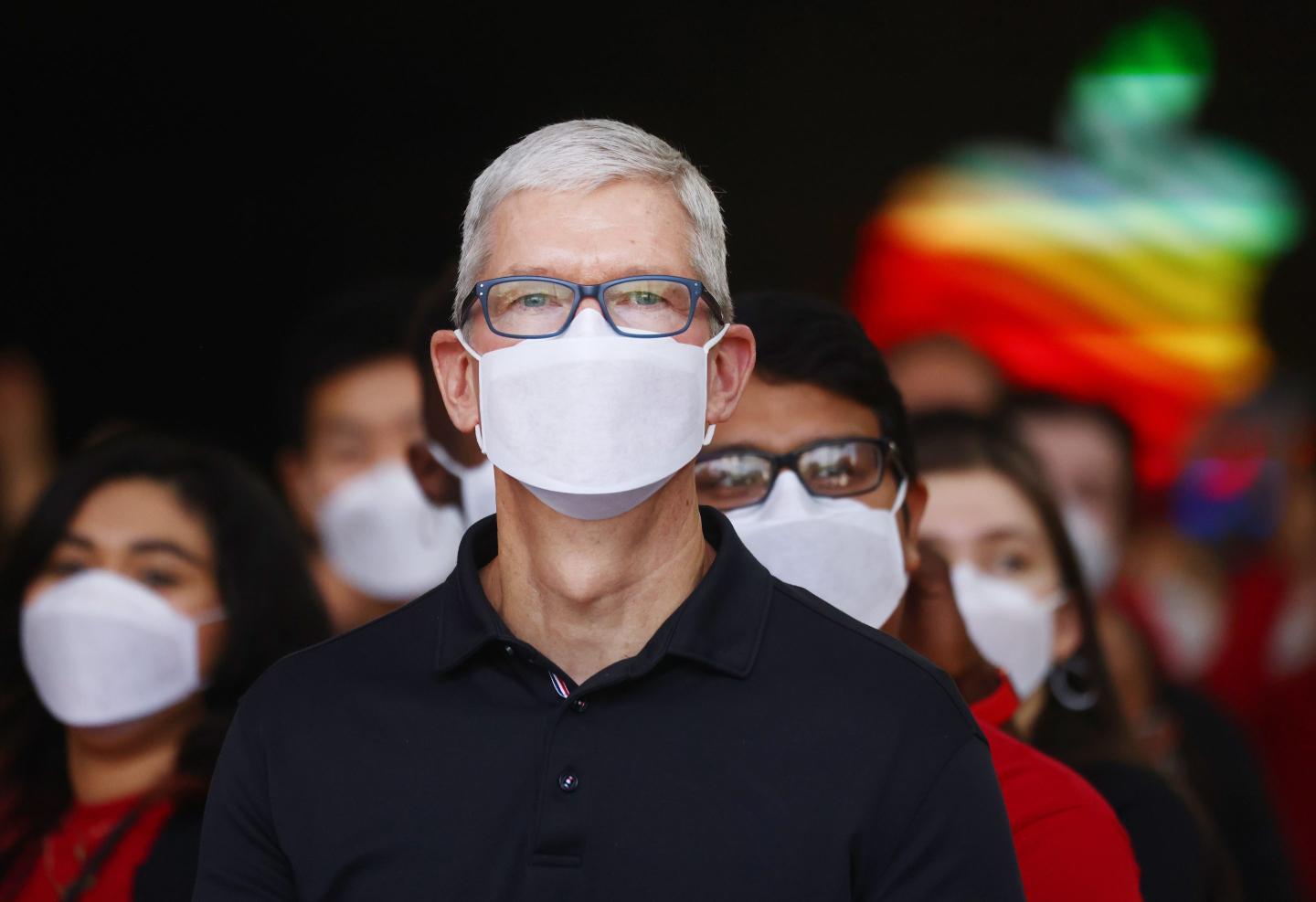 A man is wearing a mask with the Apple logo behind him.