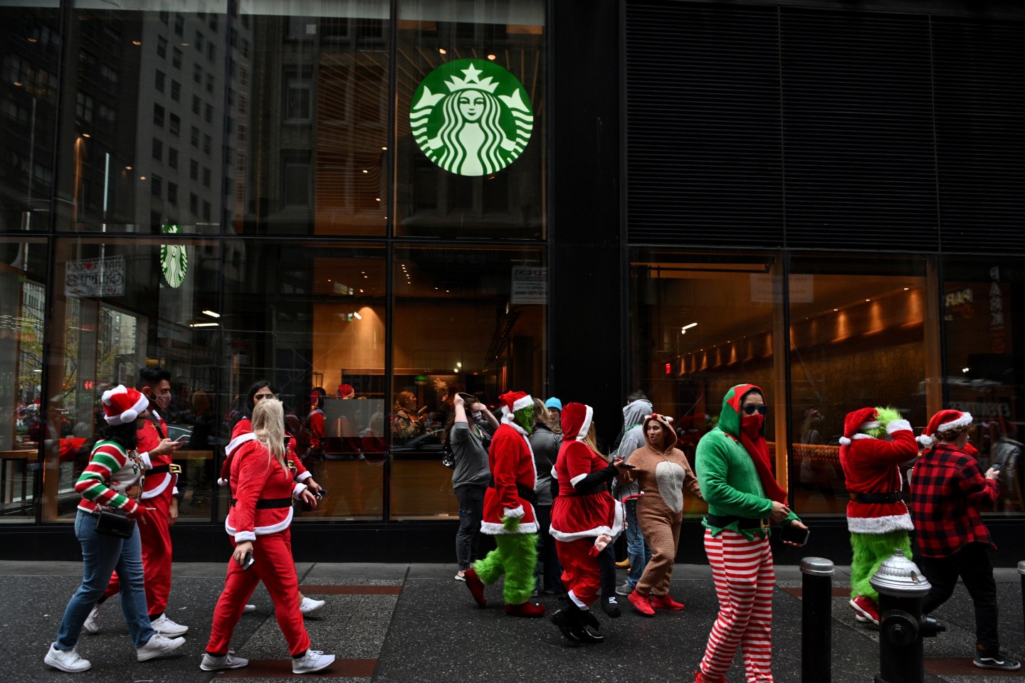 People dressed as Santa walk past a Starbucks.