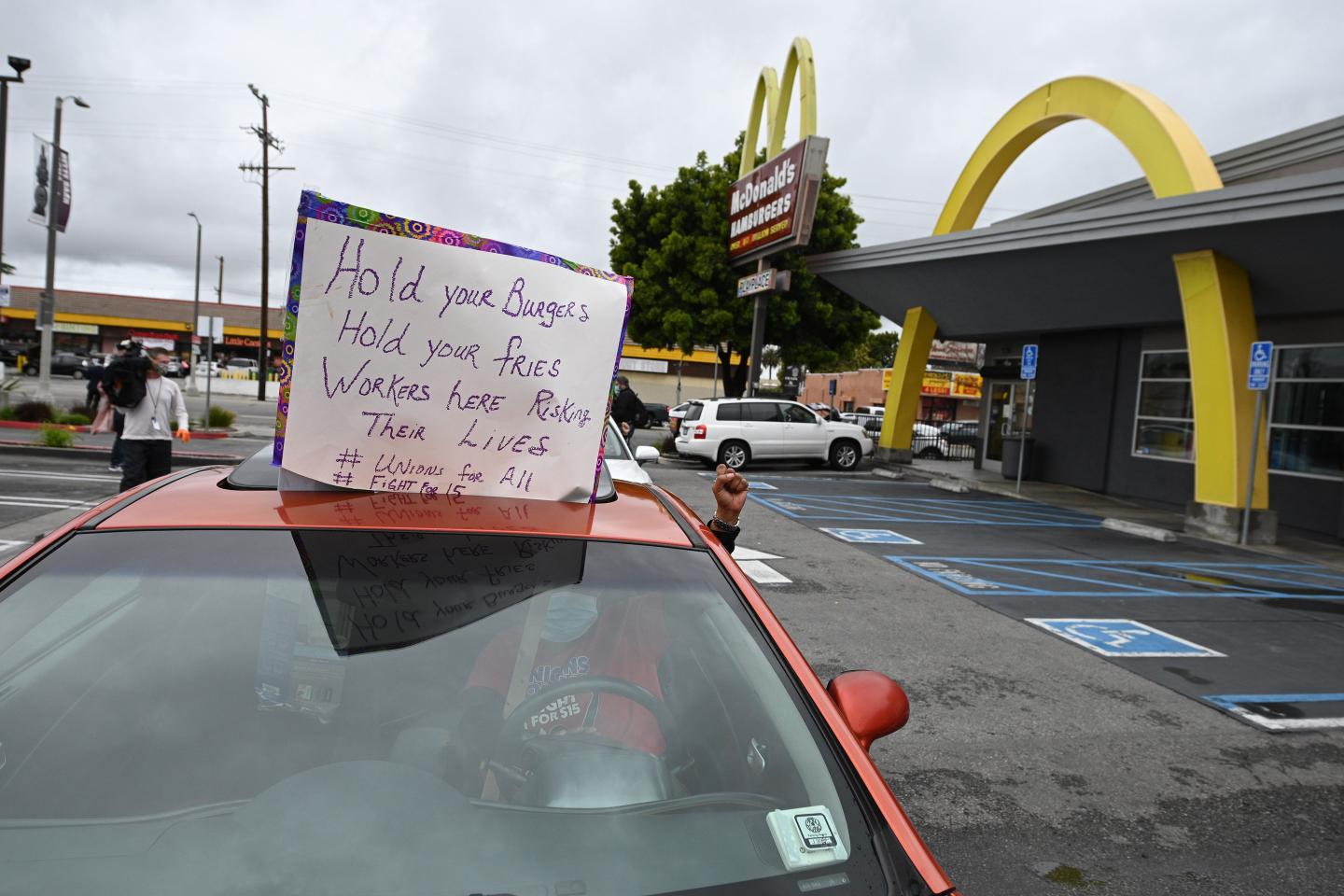 a person in a car holding their fist in the air outside a McDonald's