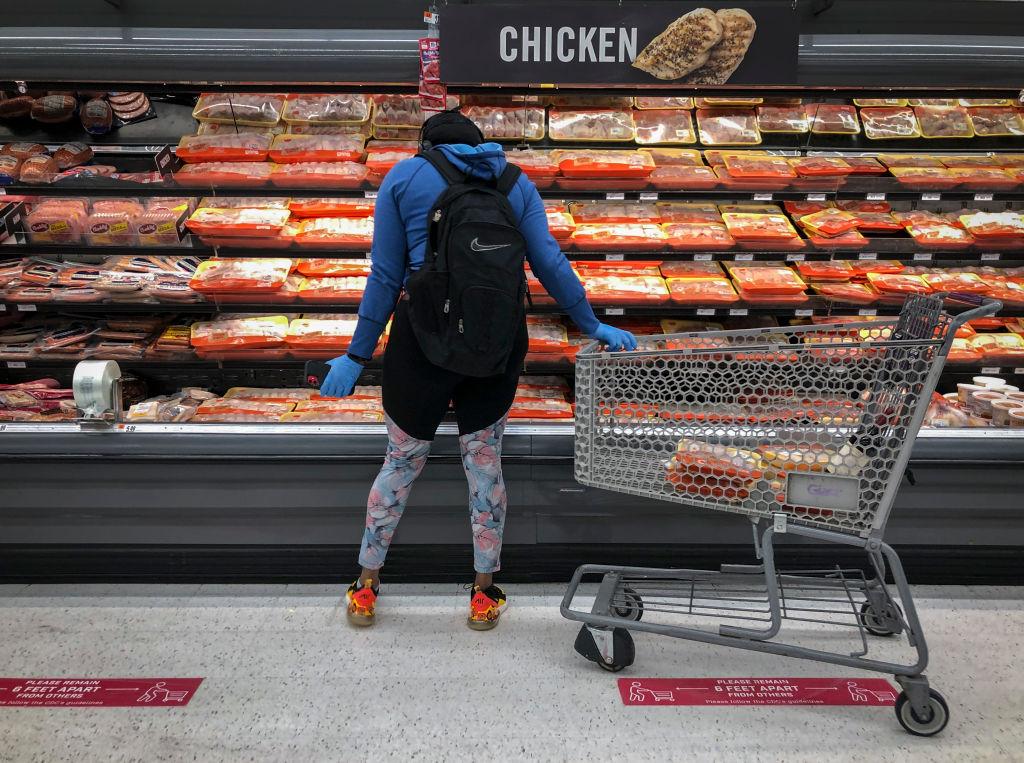 A shopper in the meat section at a grocery store.
