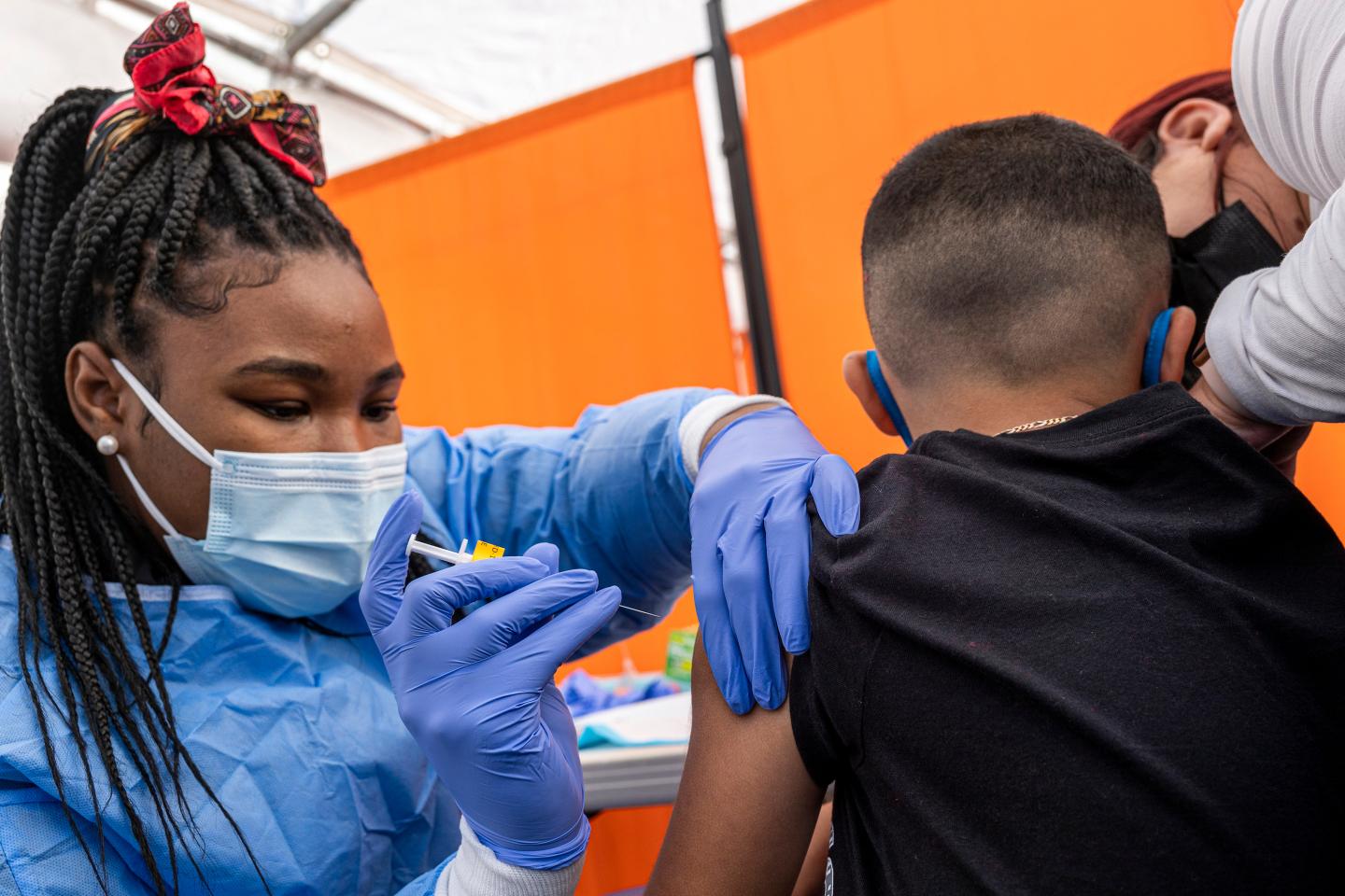 A woman administers a dose of the COVID vaccine to a child