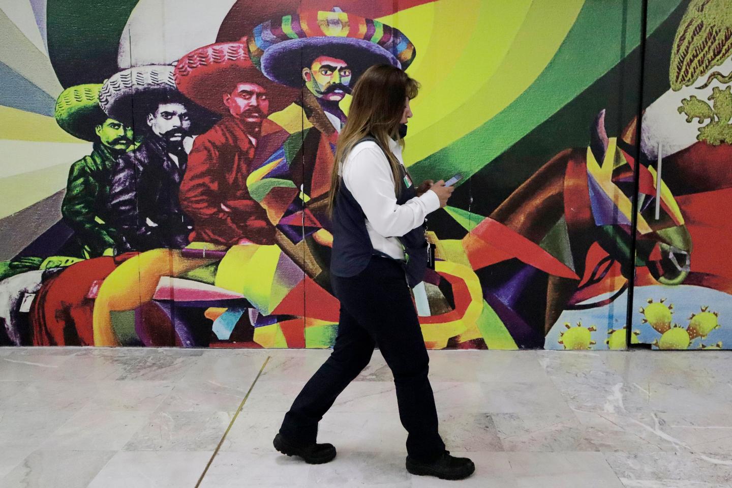 A person walks in front of a mural in Mexico City.