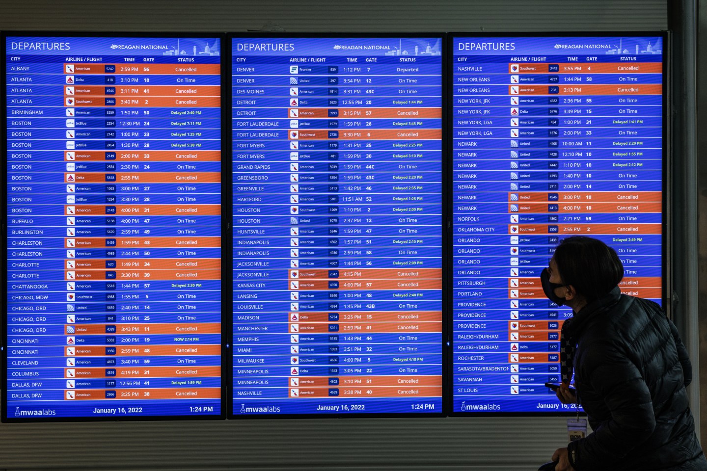 A traveler looks at flight timetables displayed on a departure board at Ronald Reagan National Airport (DCA) in Arlington, Virginia, U.S., on Sunday, Jan. 16, 2022. Washington may get an inch of snow before rain starts to fall late tonight after a fast-moving winter storm knocked out power to thousands across the U.S. South and canceled and delayed flights. Photographer: Samuel Corum/Bloomberg via Getty Images