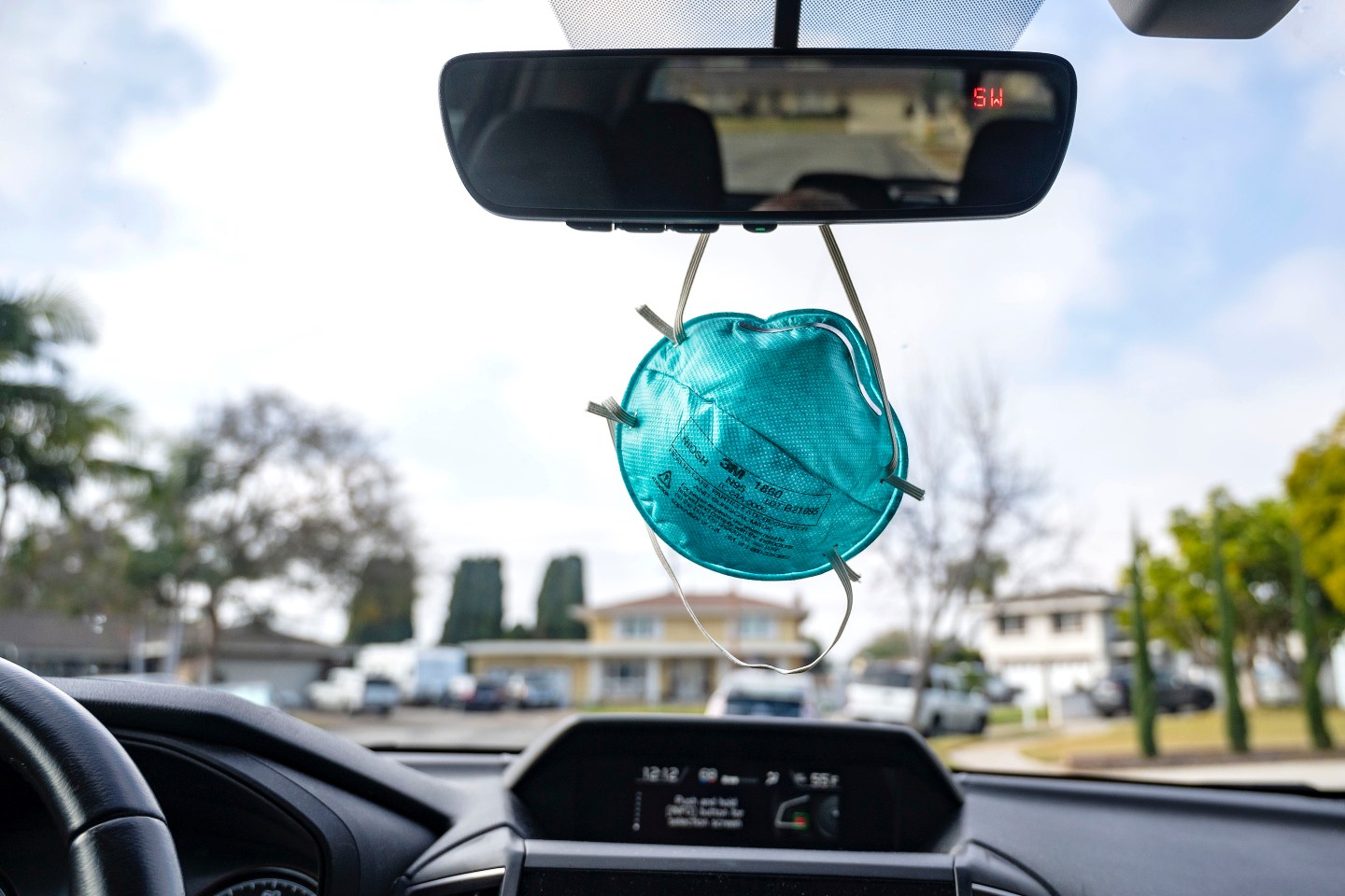 COVID face mask dangling from the rear-view mirror of a car