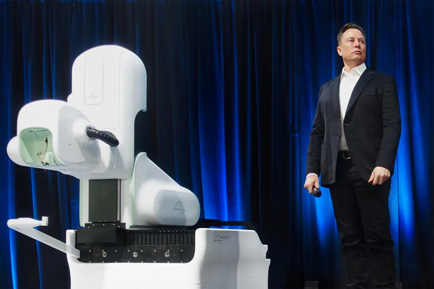 MIND-CHANGERS Elon Musk alongside the R1, the surgical robot Neuralink developed to implant its brain-computer interface devices. Musk has convinced Silicon Valley that BCIs are an investable business—though many argue he has exaggerated what they can do.