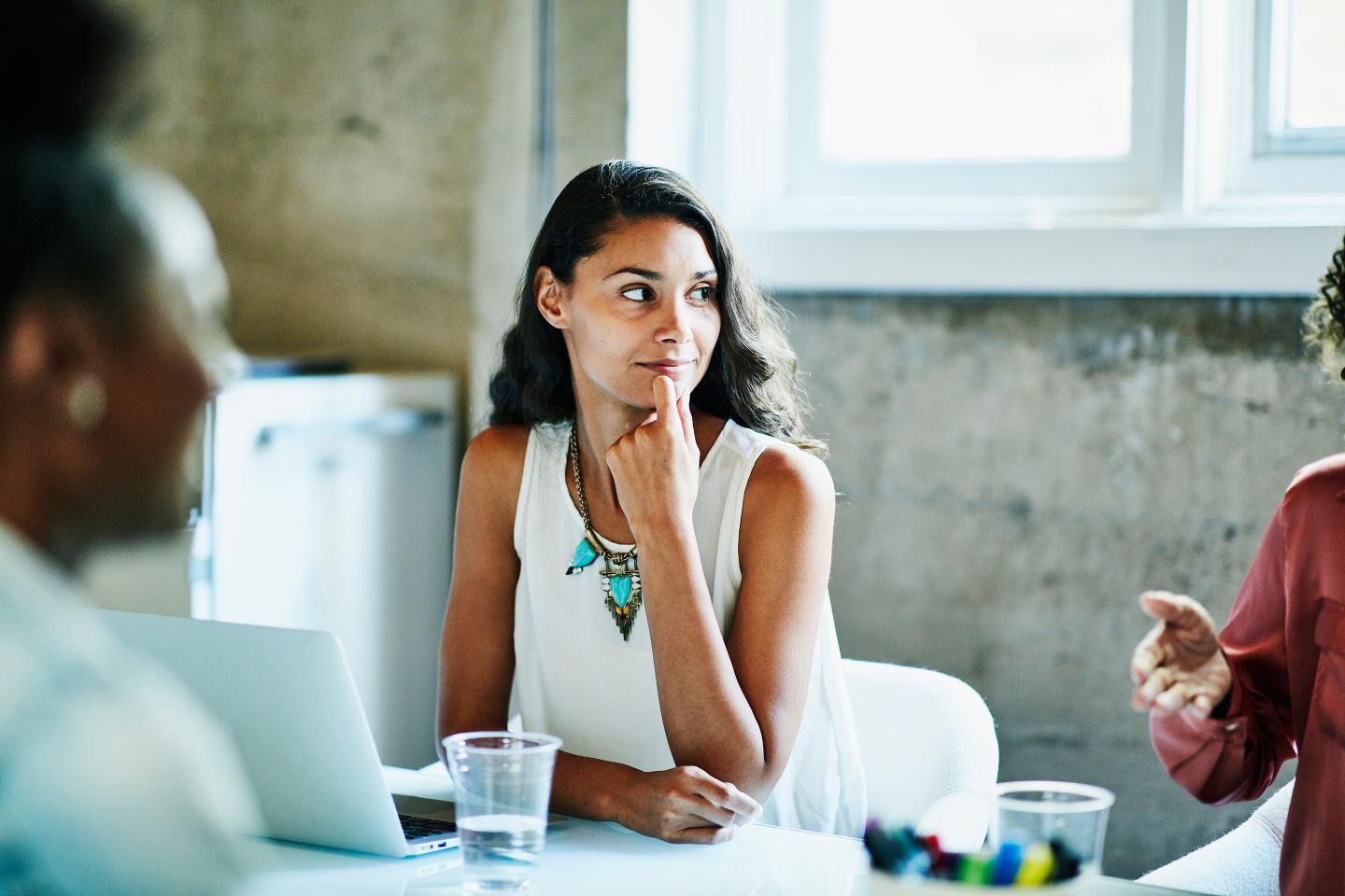 Woman of color thinking in an office meeting.