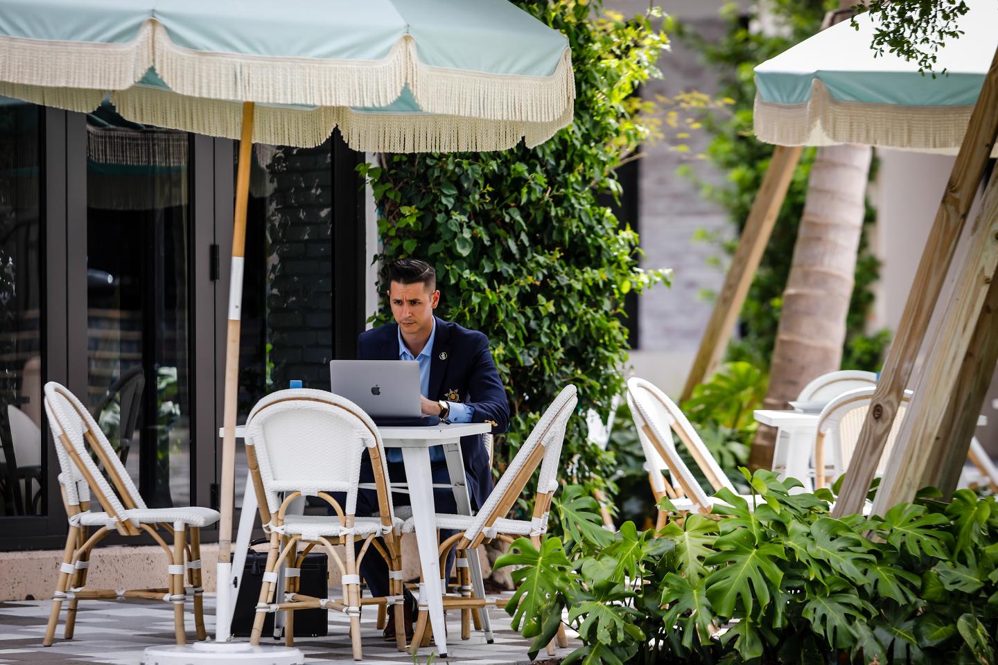 A customer works on a laptop computer in the outdoor dining area of Pura Vida restaurant on Rosemary Avenue in West Palm Beach, Florida.