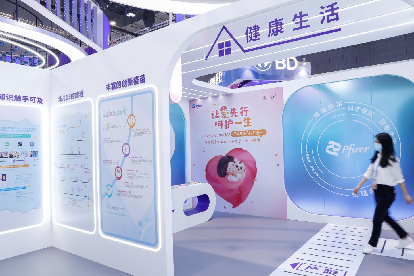 A woman walks past a Pfizer booth at a trade show in Shanghai