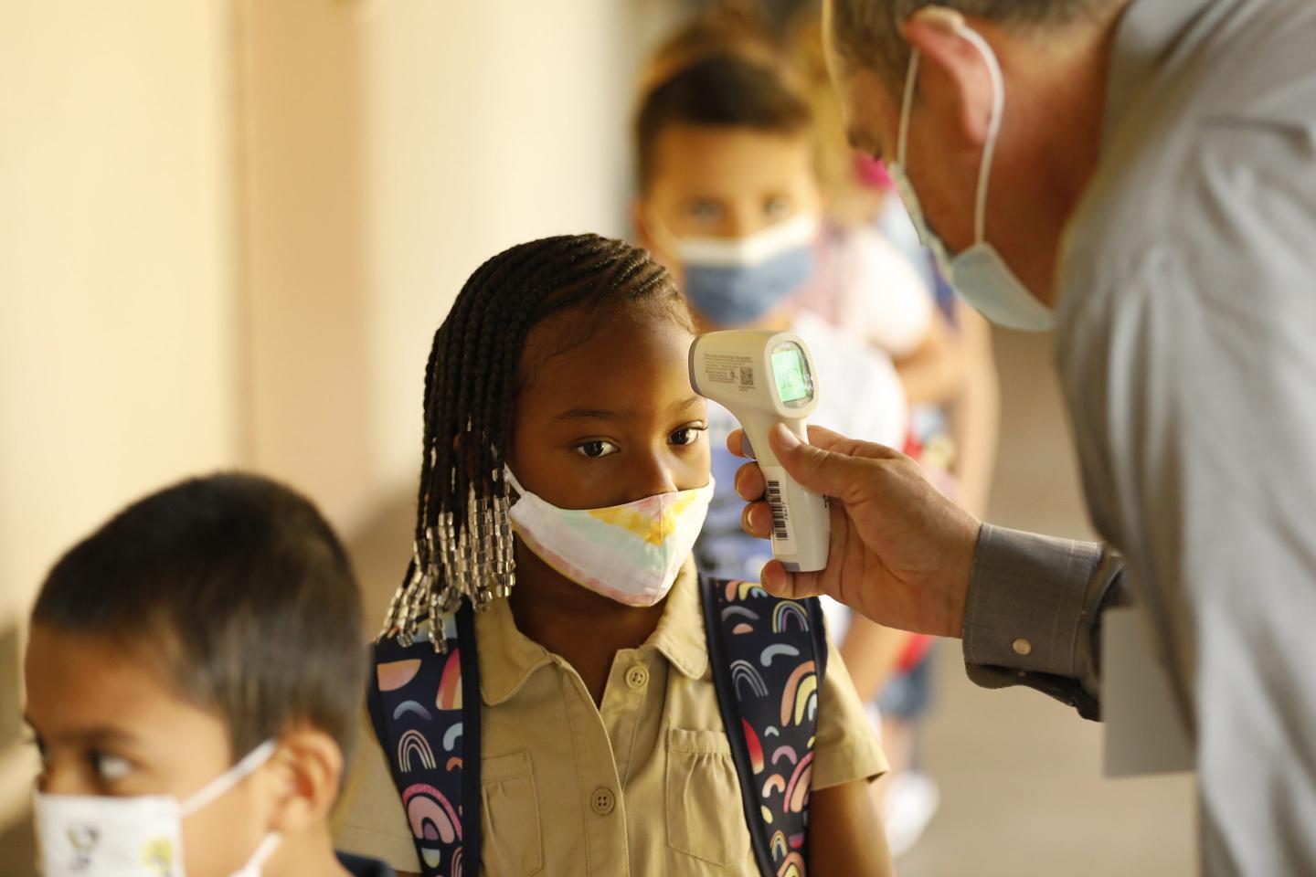 Children get their temperatures taken at school
