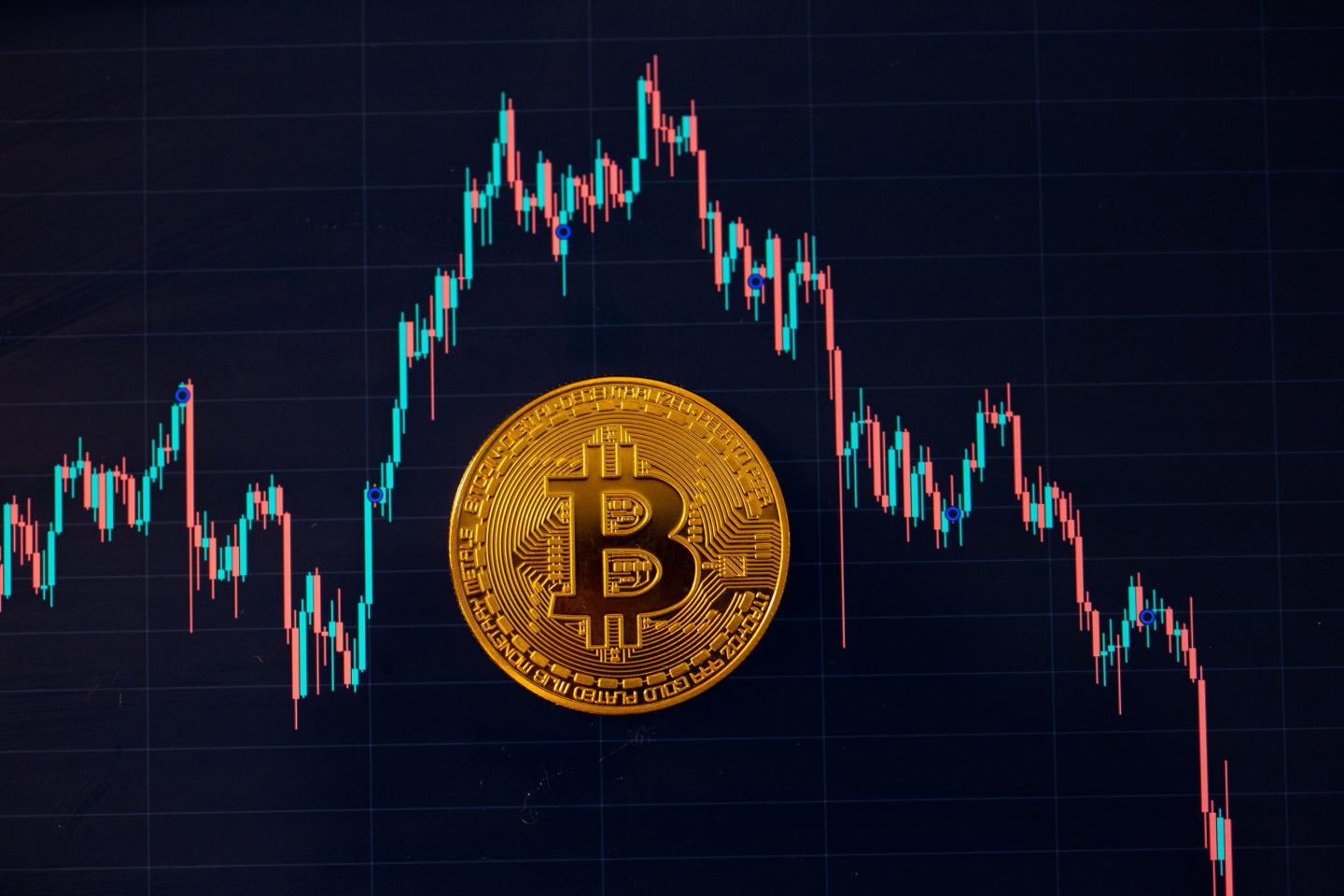 A Bitcoin coin lies on a screen showing the Bitcoin to U.S. dollar exchange rate.