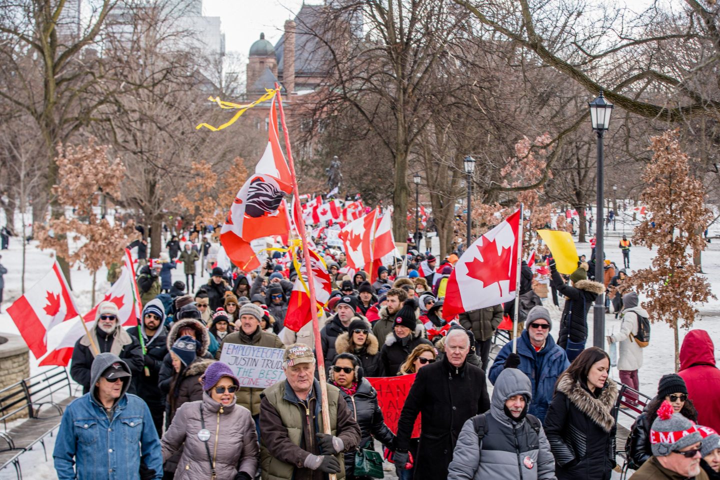 Canadians protesting the country's COVID-19 requirements march and hold flags in Ottawa.