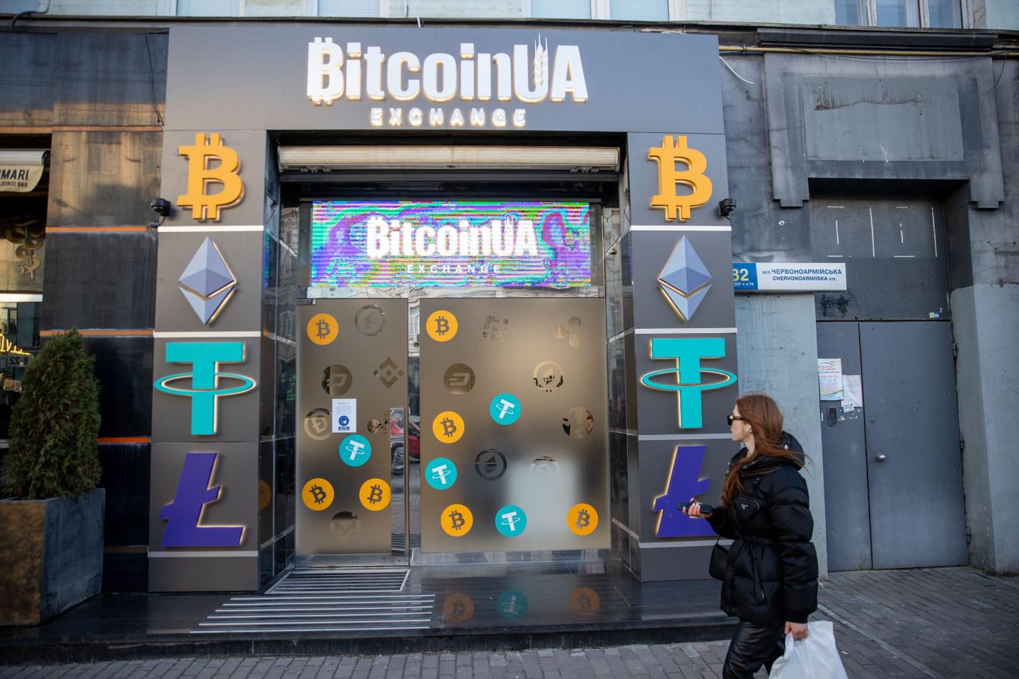 A woman walks past a Bitcoin cryptocurrency exchange in Kyiv, Ukraine