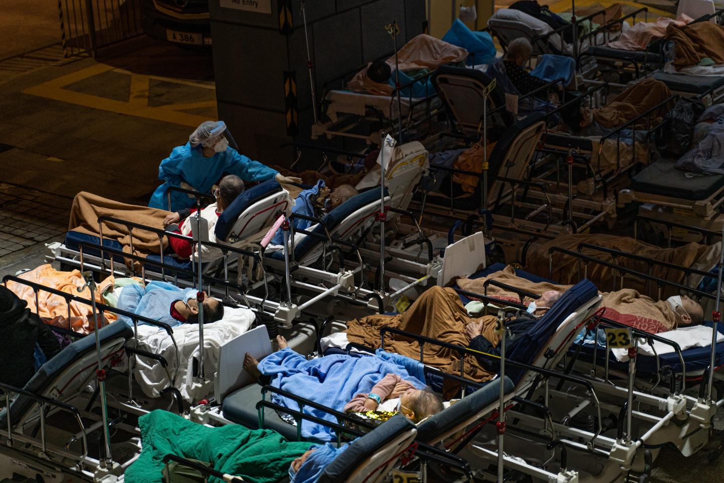 COVID patients in Hong Kong lie in beds outside while being treated by a doctor wearing personal protective equipment