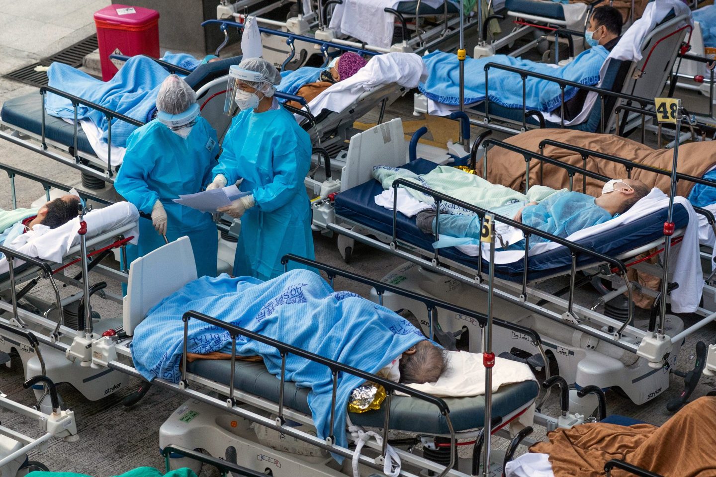 Beds with COVID patients are being treated by two doctors wearing personal protective equipment outside the Caritas Medical Center in Hong Kong