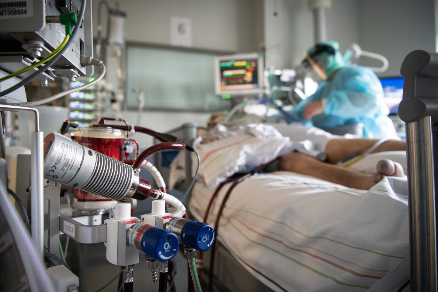 dpatop &#8211; PRODUCTION &#8211; 16 February 2022, Hessen, Fulda: A nurse cares for a patient who is seriously ill with corona in the intensive care unit of the hospital in Fulda. In the foreground is an ECMO machine to which the man is connected. Many patients with severe courses of the disease spend several weeks in the intensive care unit, and around half of the artificially ventilated patients die. Photo: Boris Roessler/dpa (Photo by Boris Roessler/picture alliance via Getty Images)