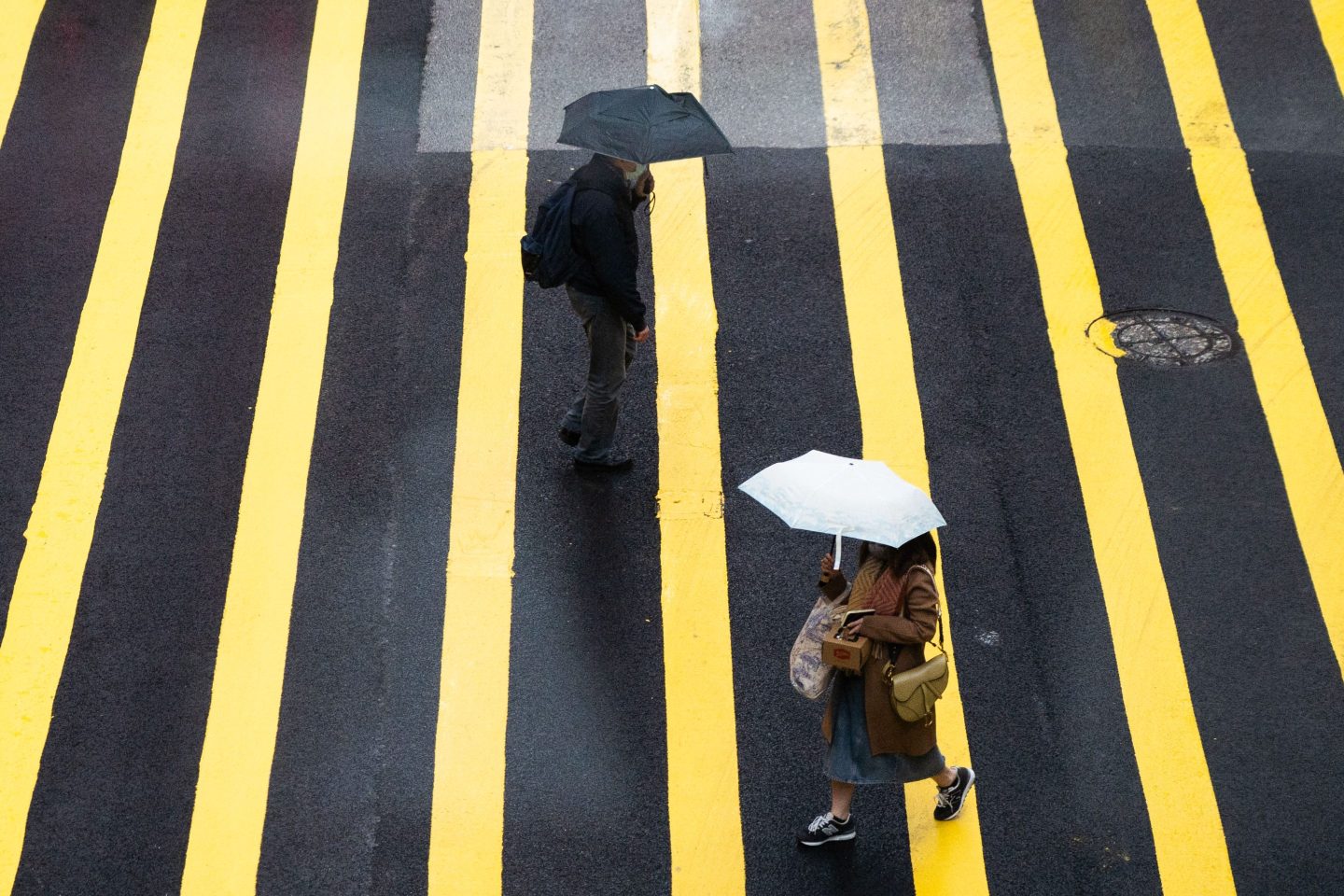 Pedestrians with umbrellas walk across a cross-walk in the rain in Hong Kongs Central area on Feb. 19, 2022.